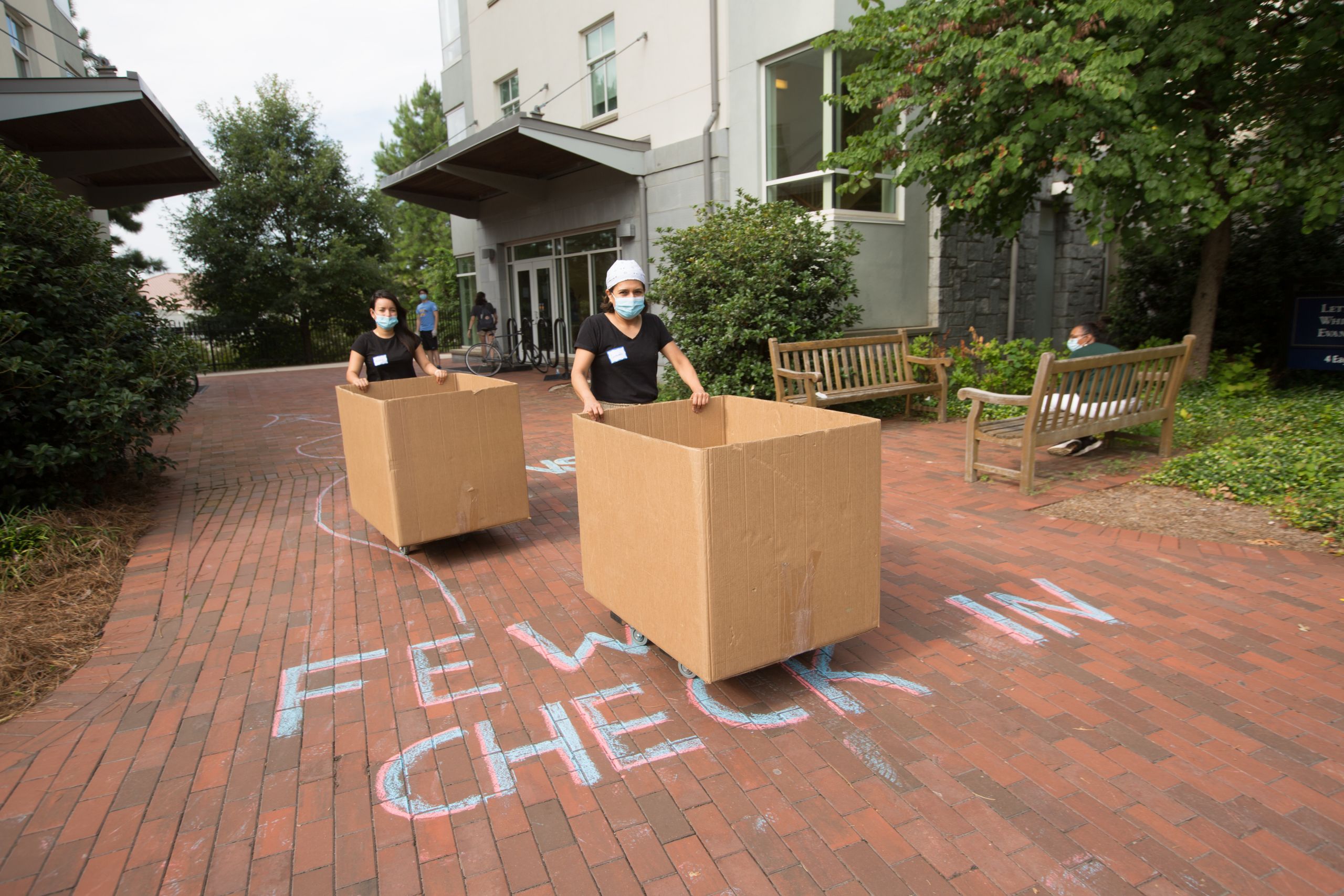 Move In helpers push bins of student belongings to a residence hall