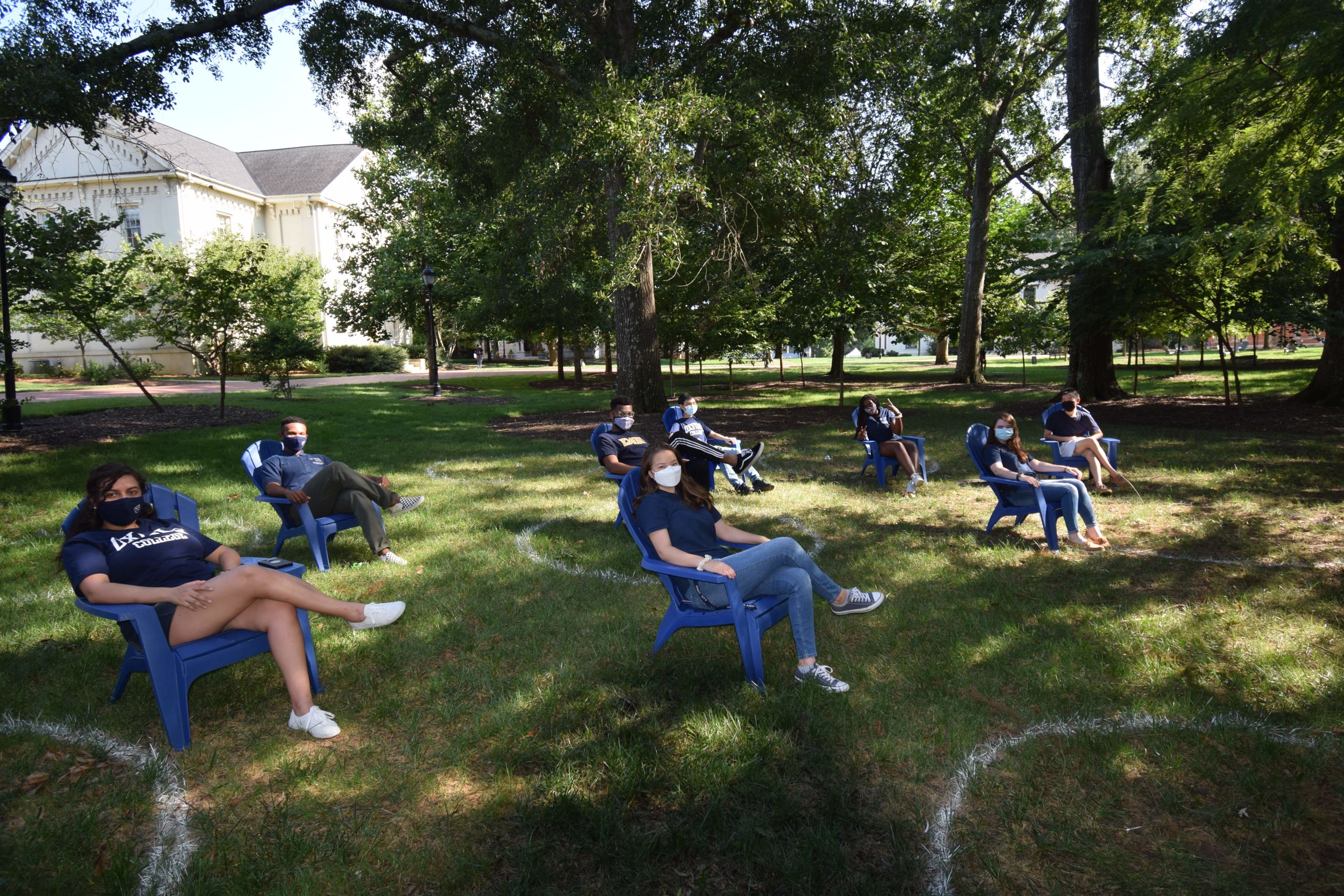 Students wearing face coverings sit in chairs that are set apart on the Oxford quad