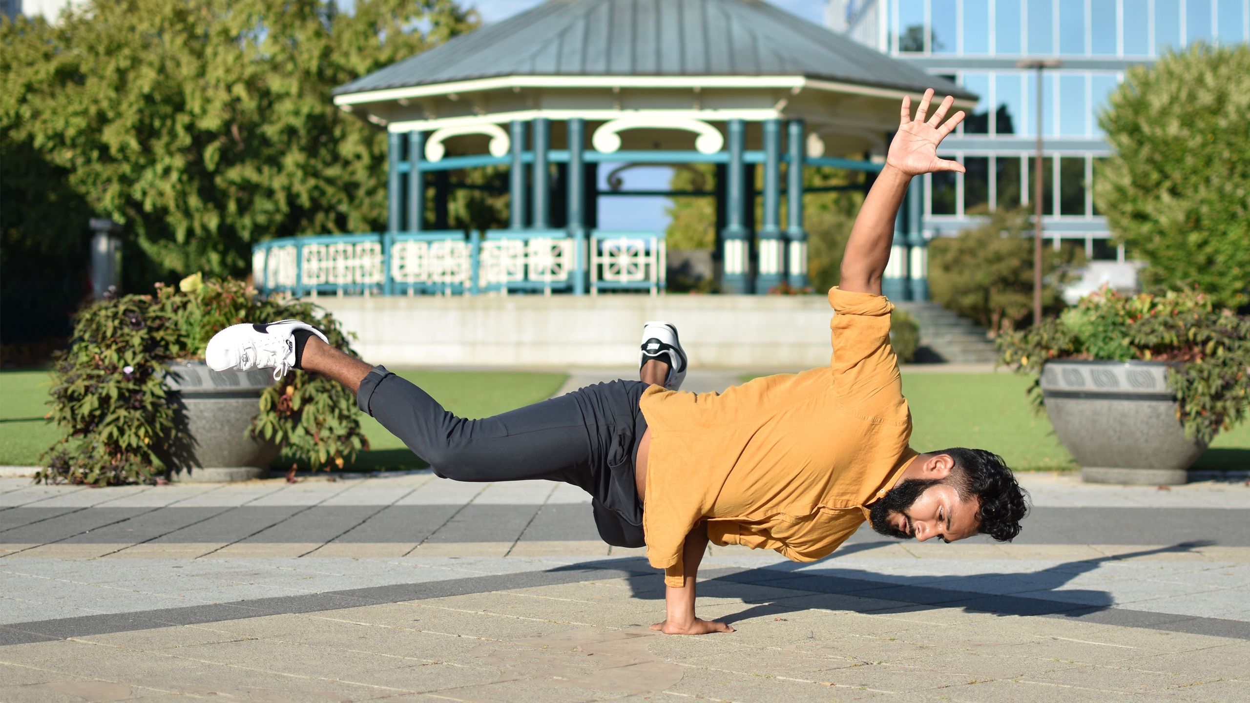 Julio Medina performs a dance move where he balances on one hand, holding his body parallel to the ground.