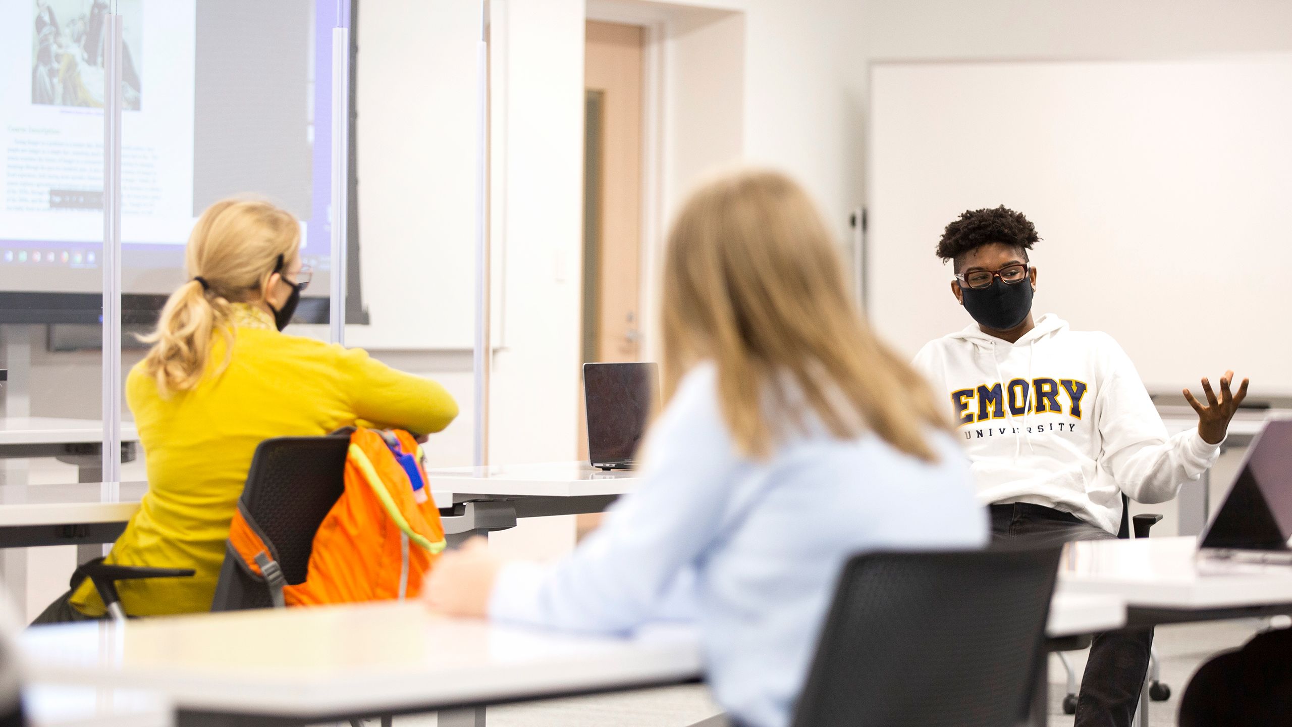 Students wearing face coverings sit at tables in an Emory classroom
