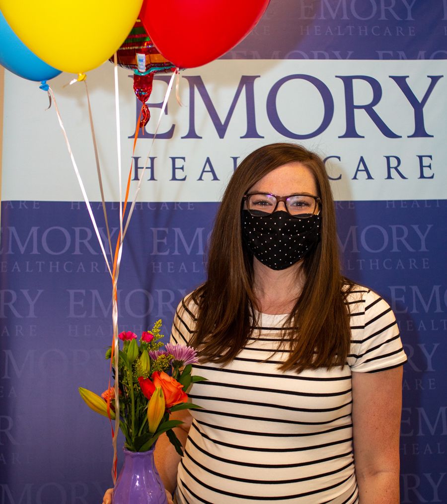 a woman in a mask holds balloons and flowers