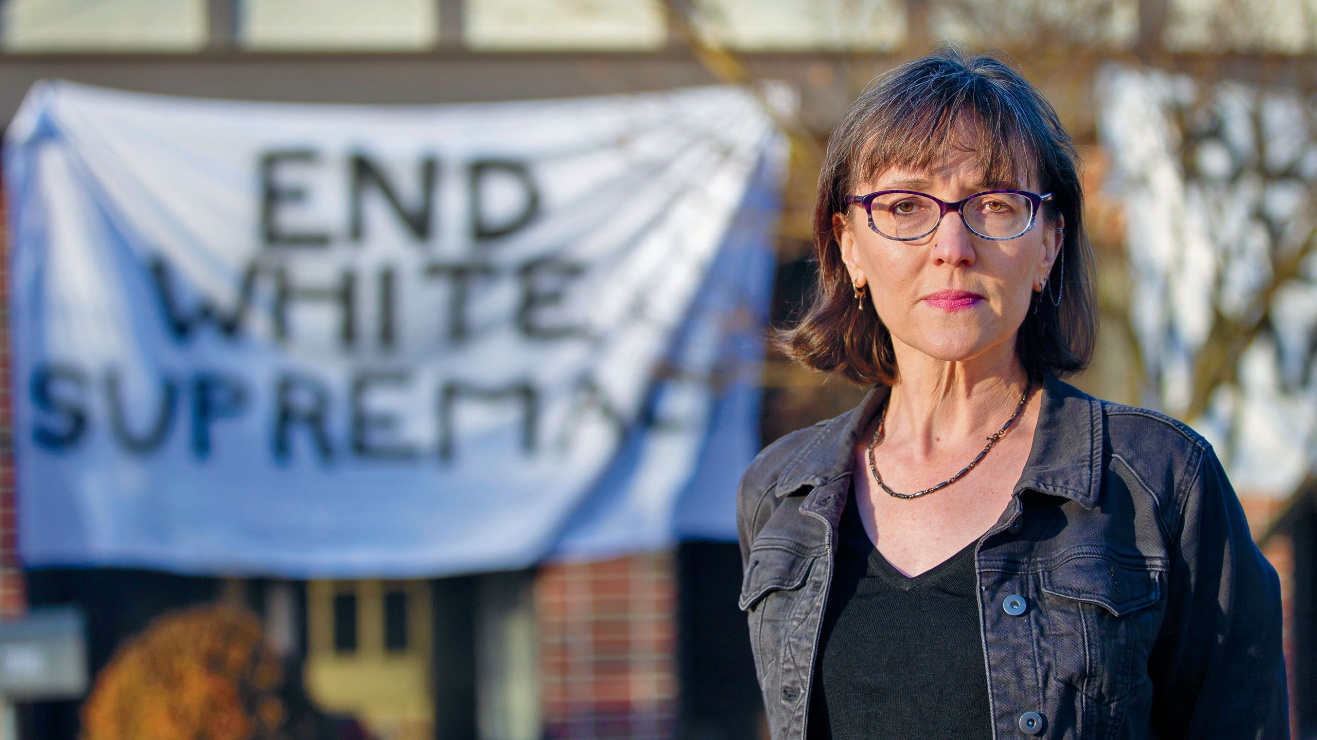 A photo of Hannah Copper standing in front of her home with the sign that reads end white supremacy.