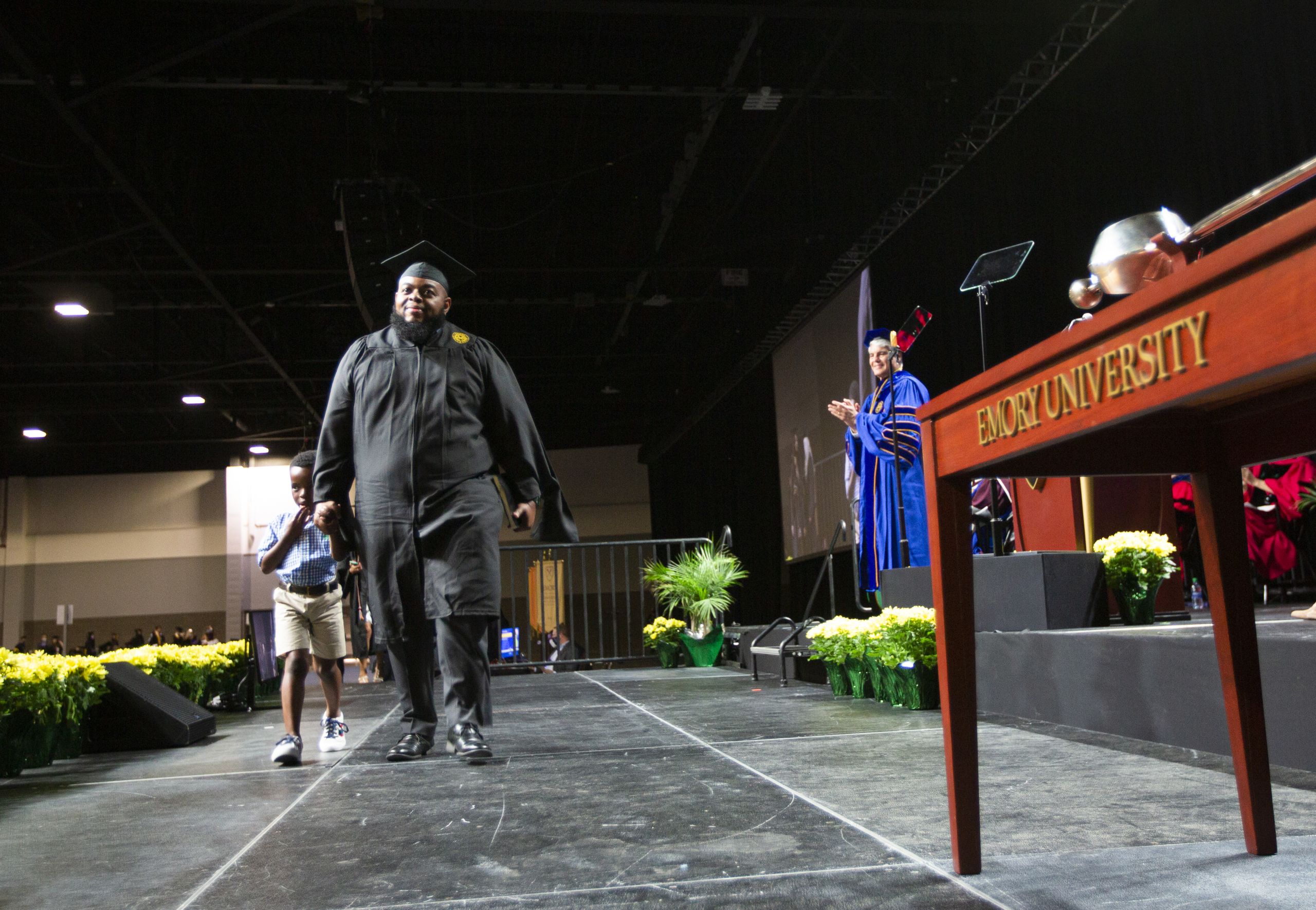 Graduate crossing stage with son