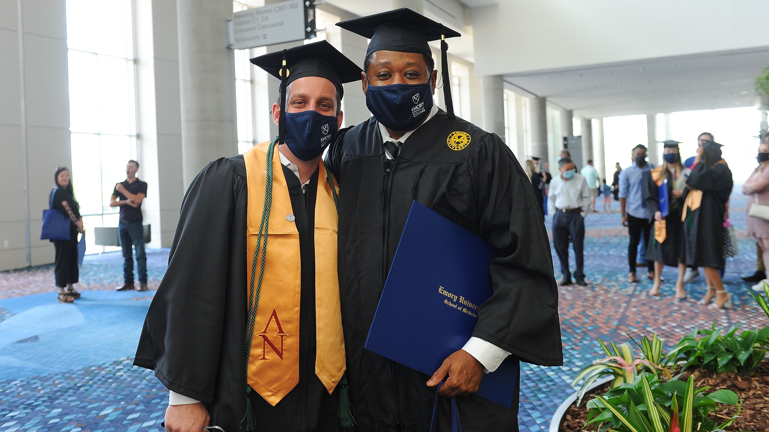 two graduates pose for photos outside