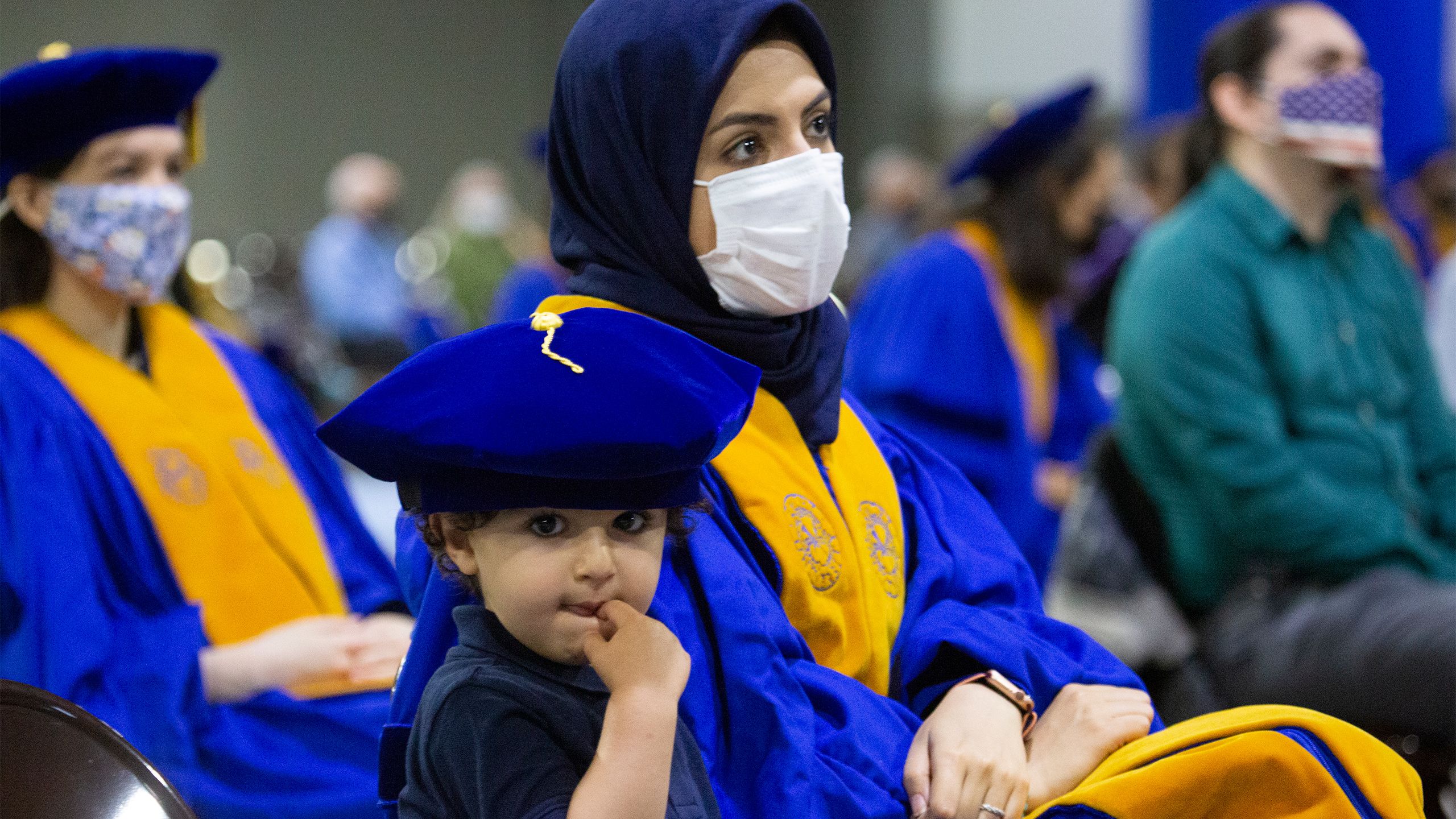 A child wears his mother's PhD cap