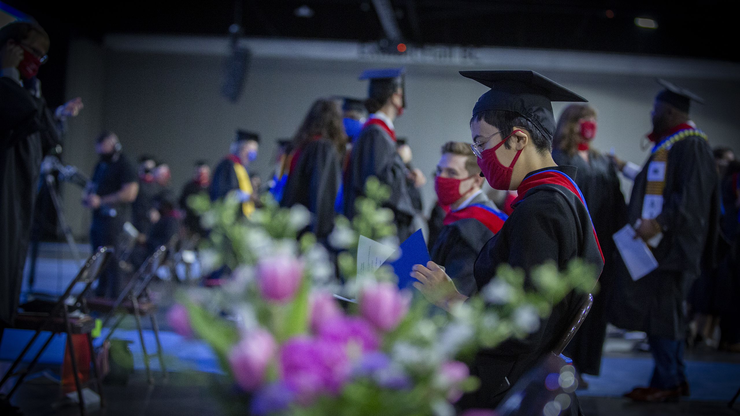 a row of graduates seated with flowers in the foreground