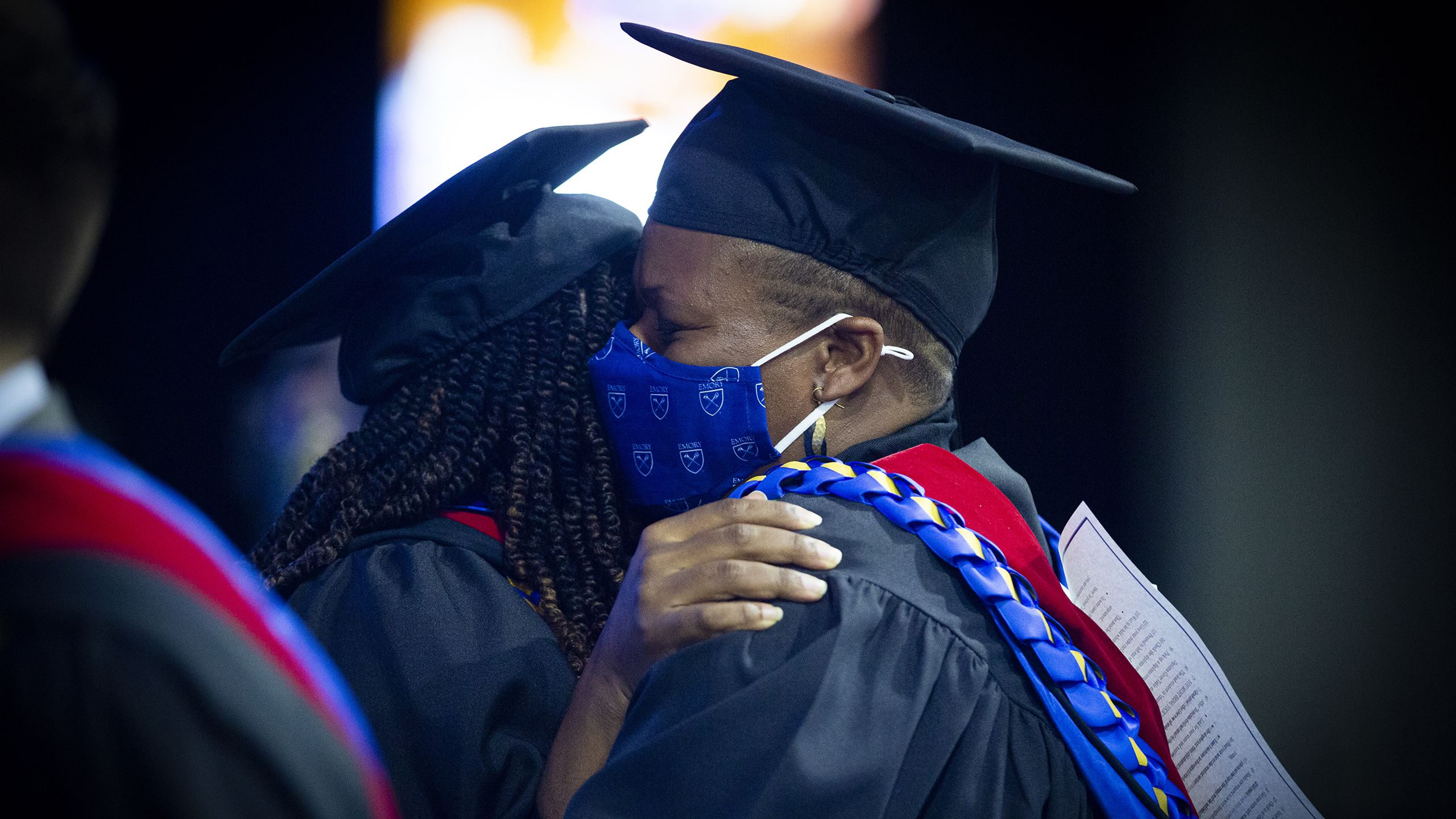 two graduates hug
