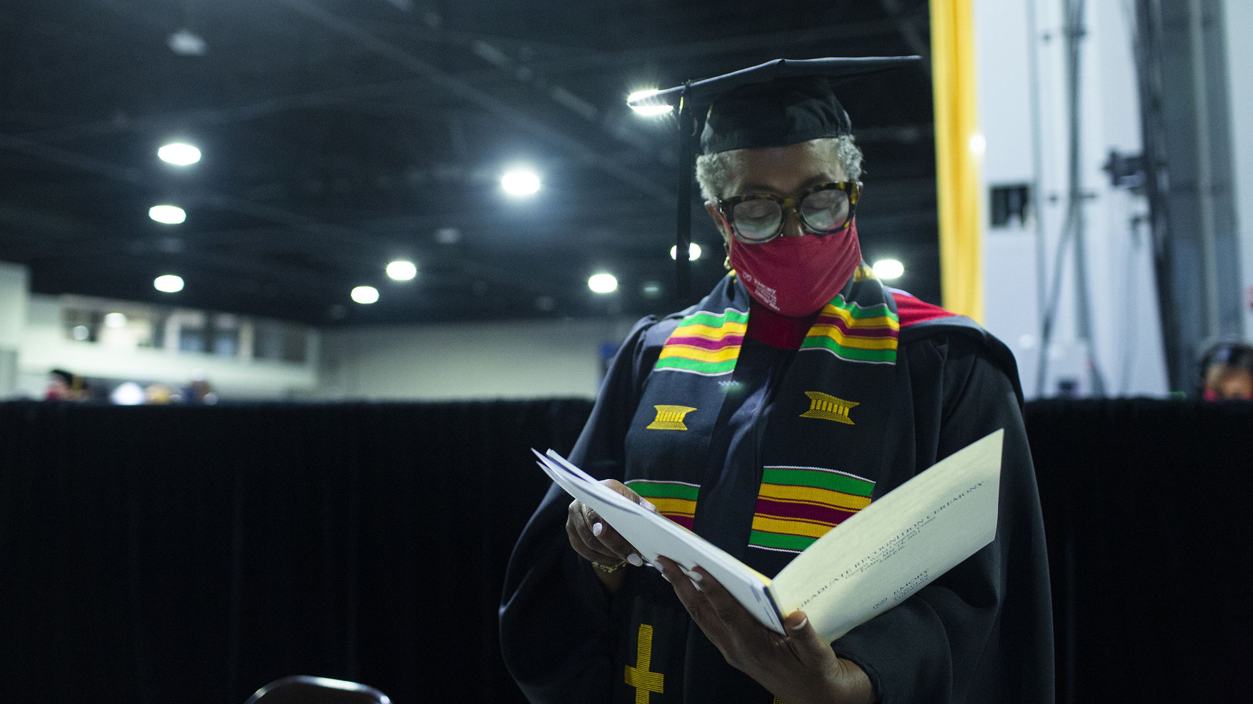 a woman in cap and gown reads from a program
