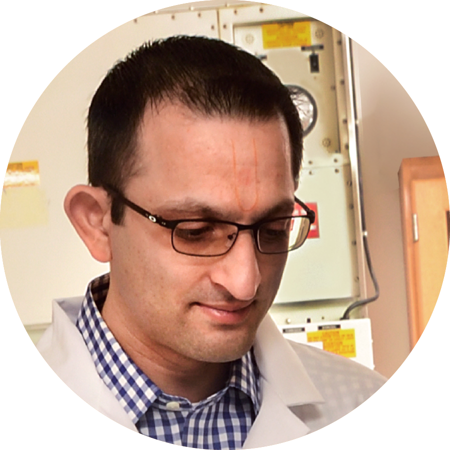 A man with brown hair and glasses in a white lab coat.