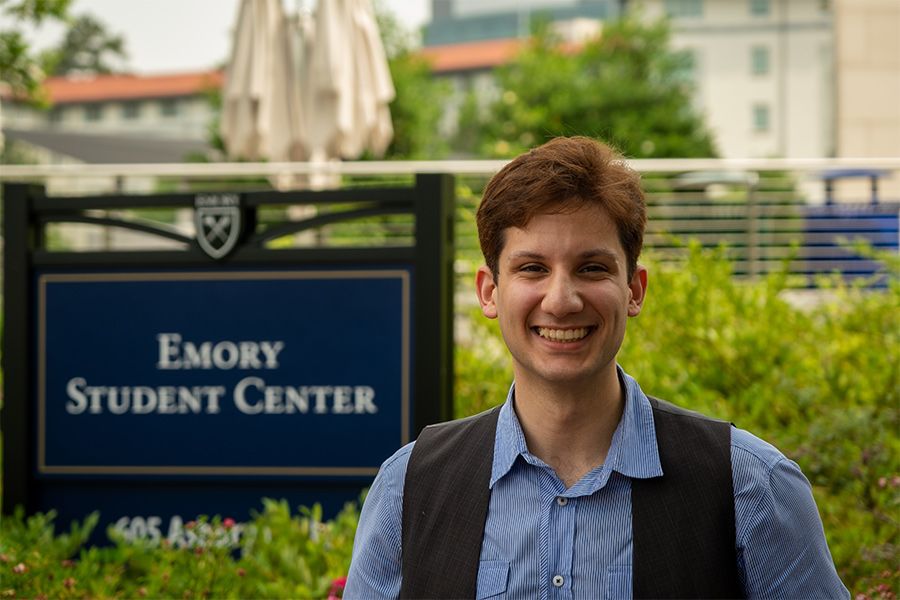 Abdallah Al-Obaidi standing by the Emory Student Center sign