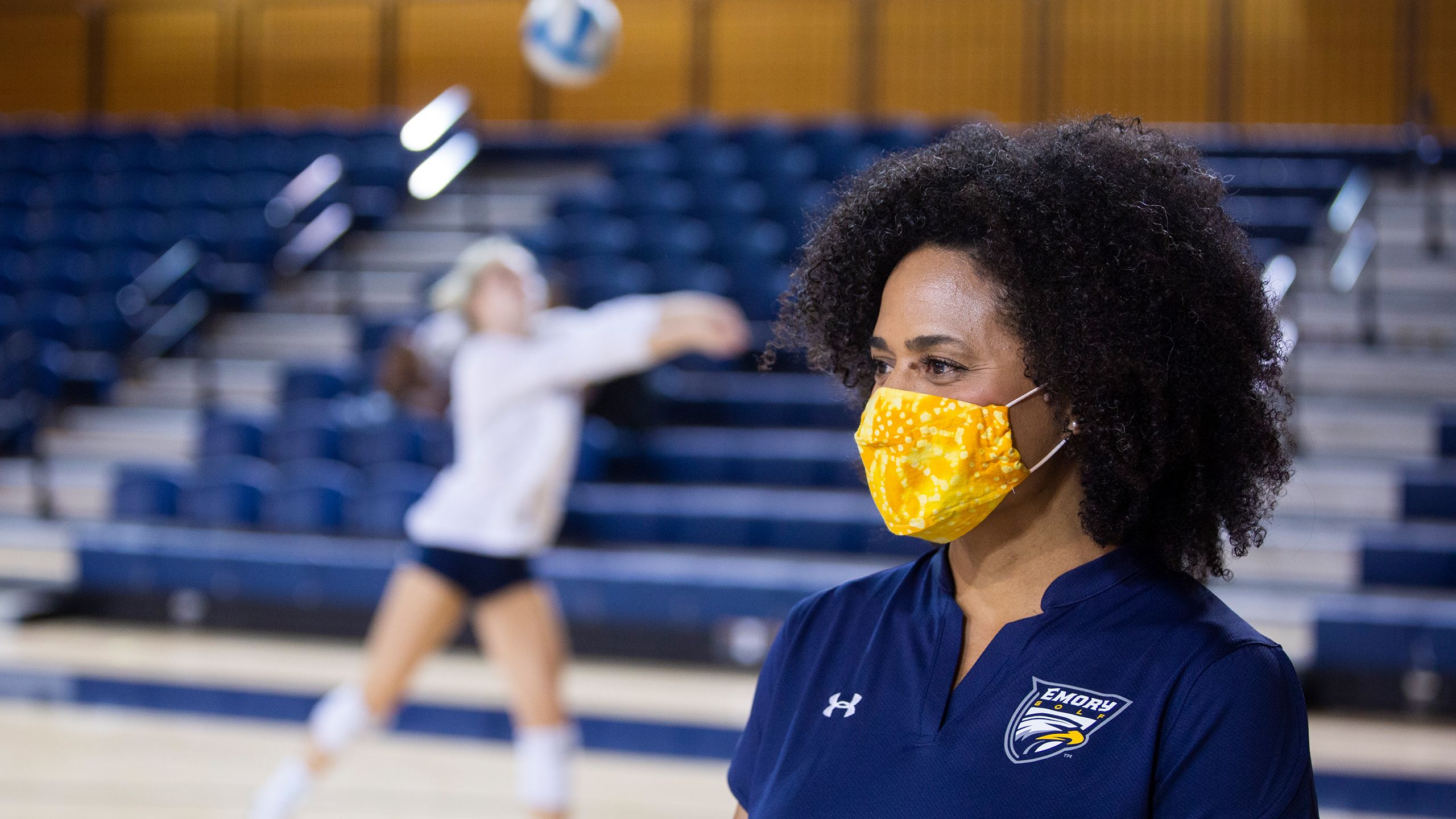 women in facing left wearing yellow mask standing in gym