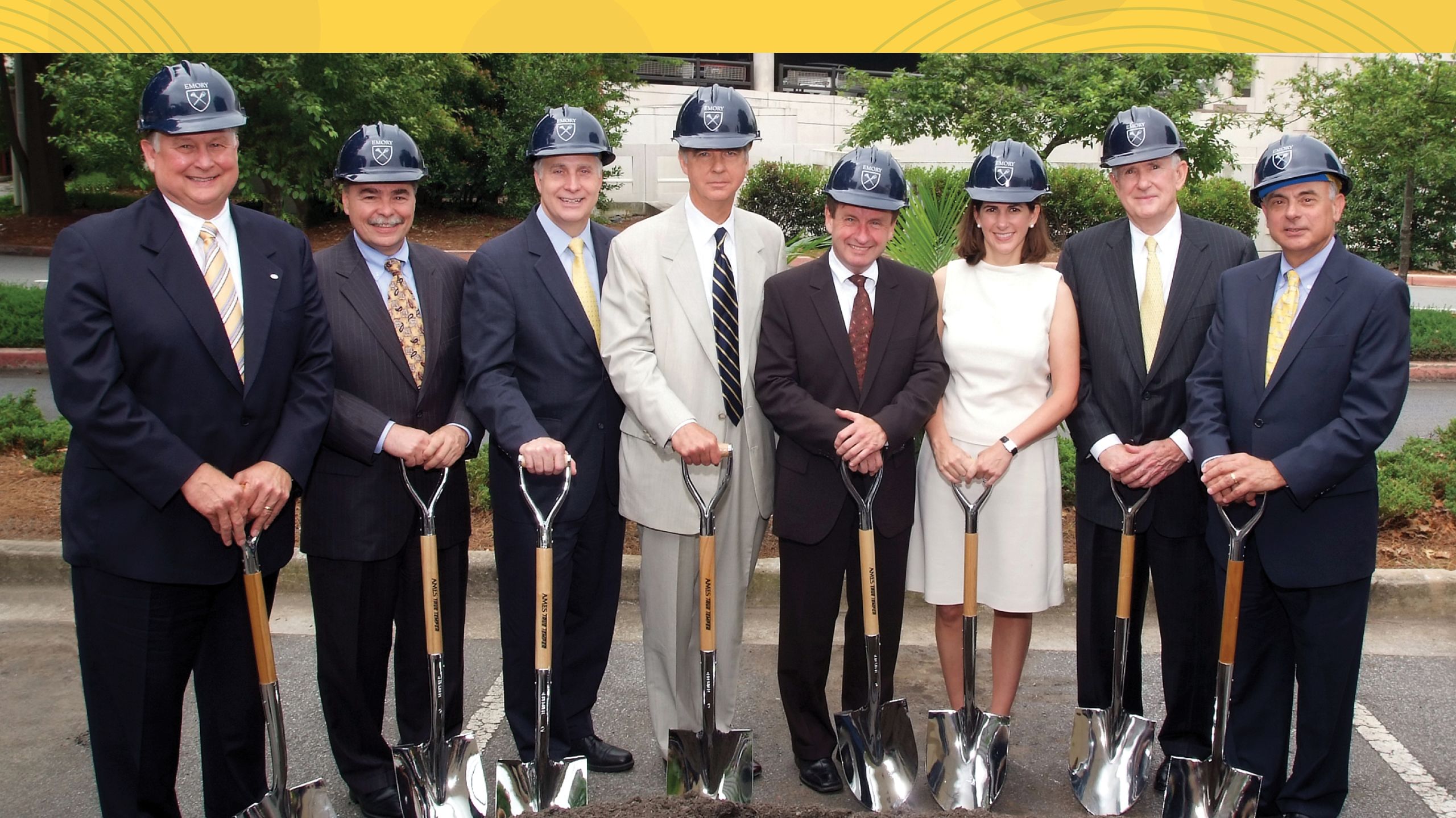 a group shot photo of people wearing hard hats and holding shovels. 