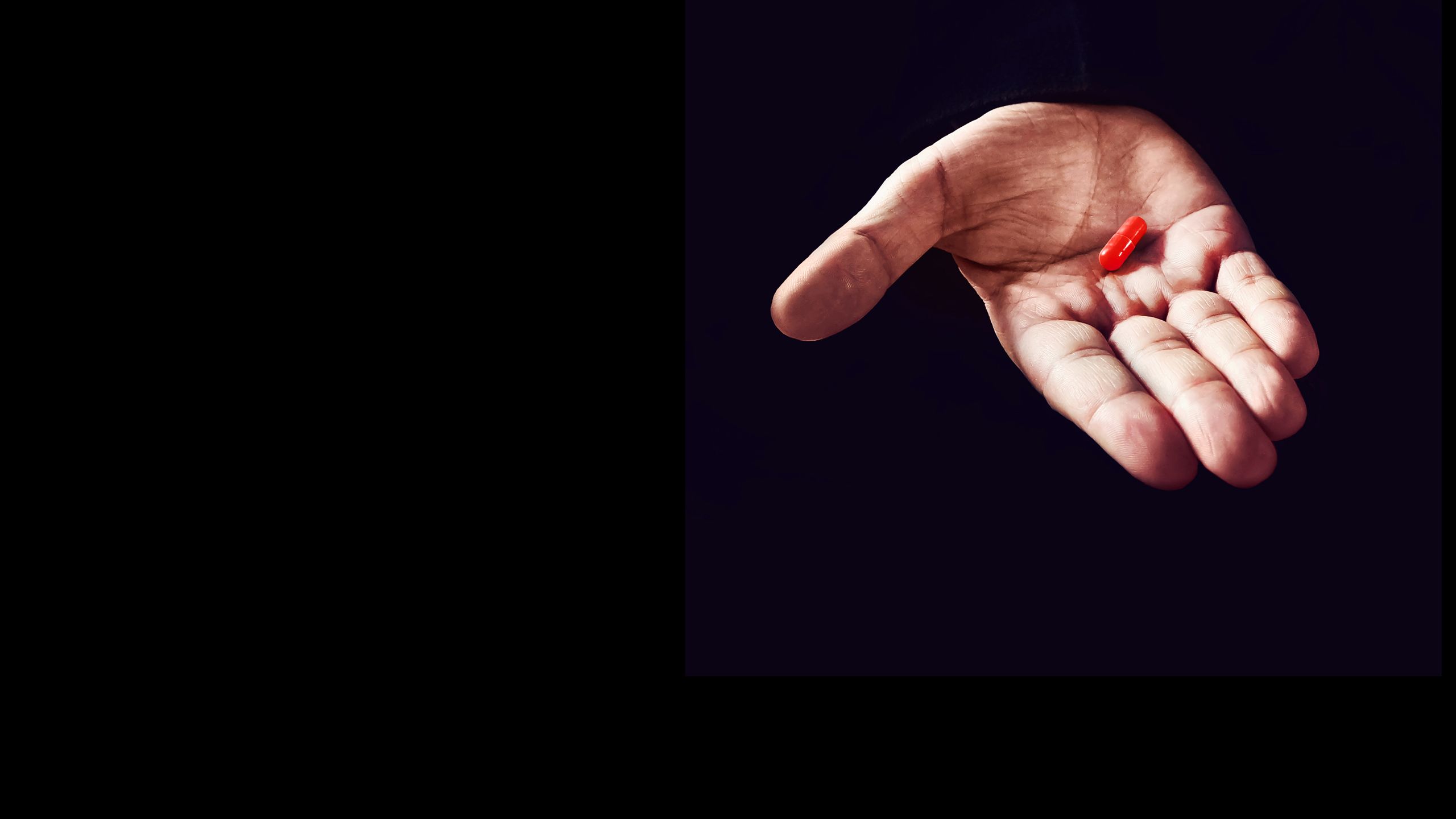 Hand holding a red pill