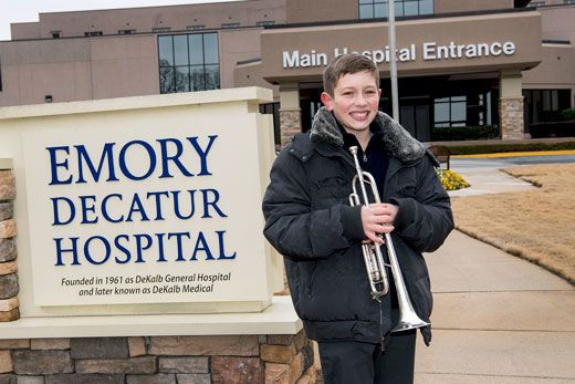 Jason Zgonc poses with his trumpet by the Emory Decatur Hospital sign