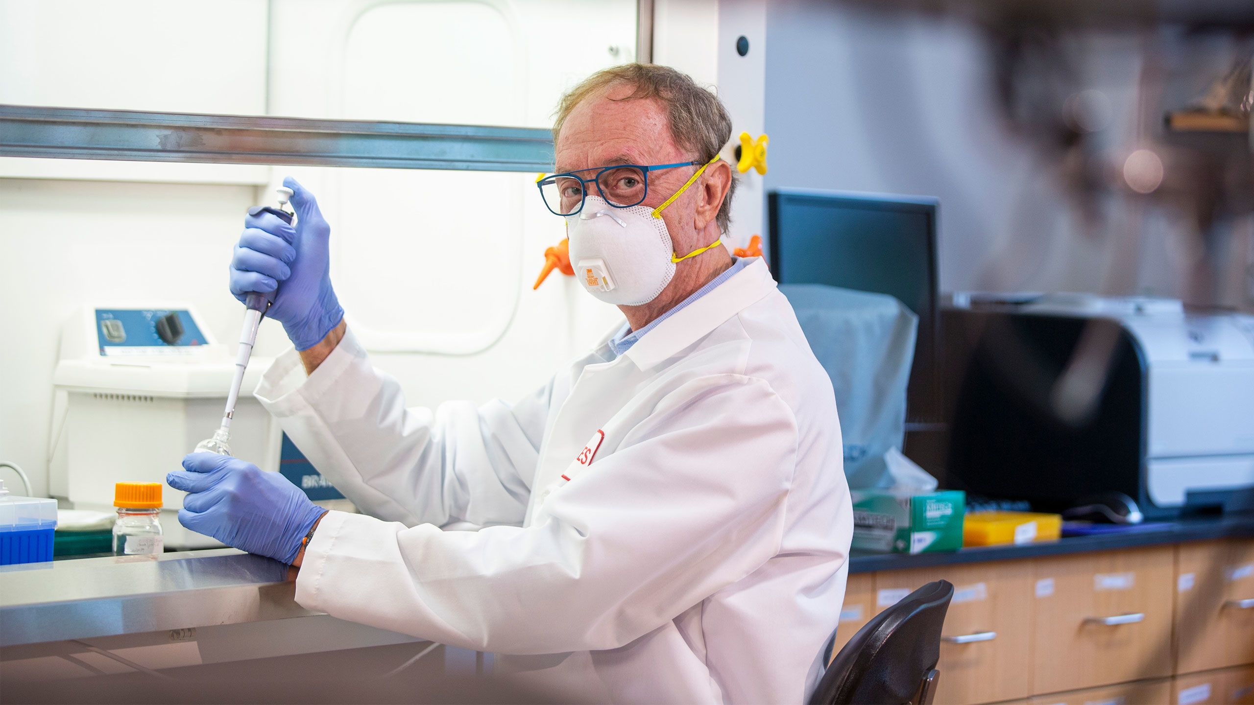 George Painter in a lab wearing a face mask and gloves