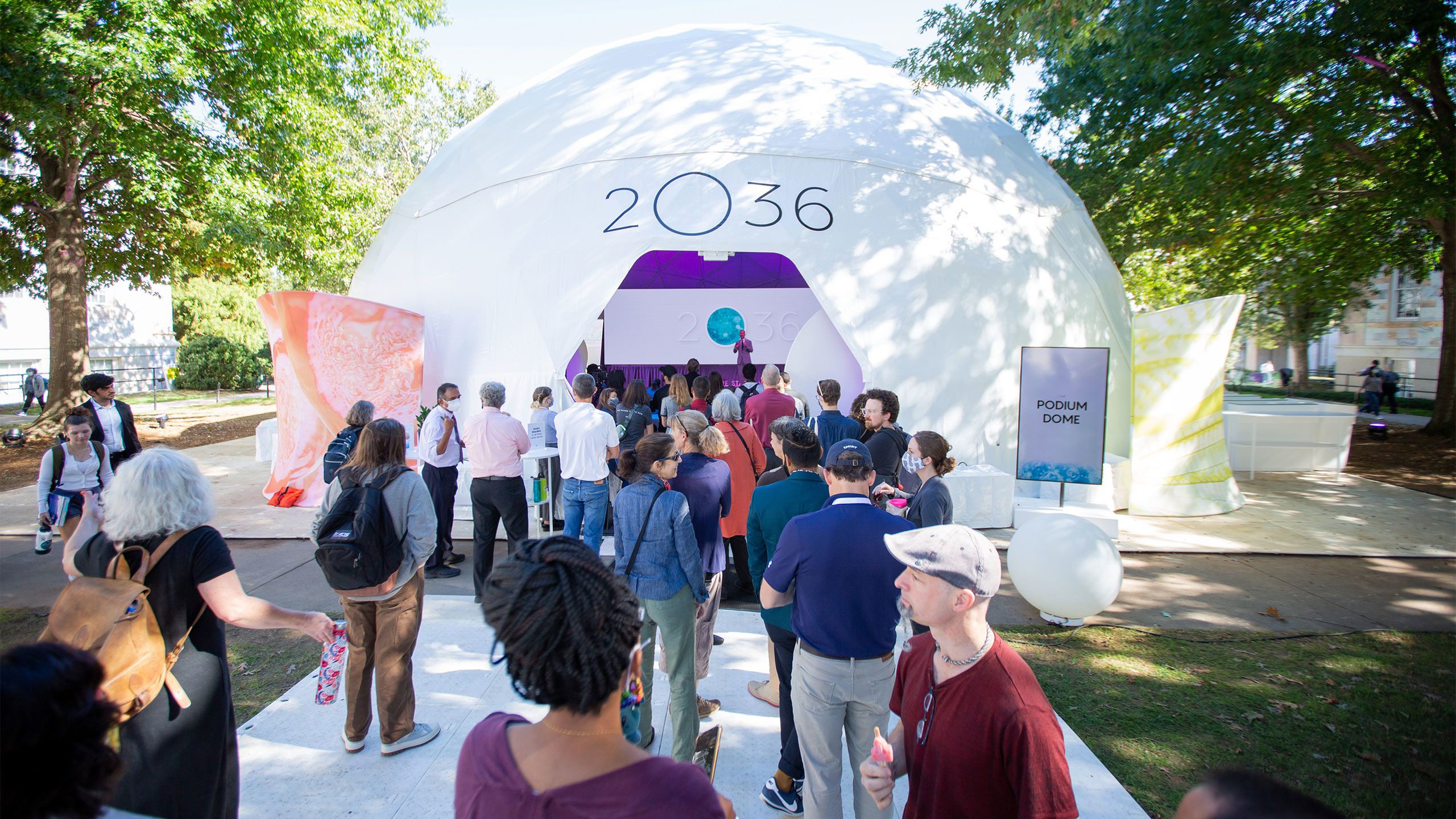 People line up to enter a futuristic 2O36 dome on the Emory quad