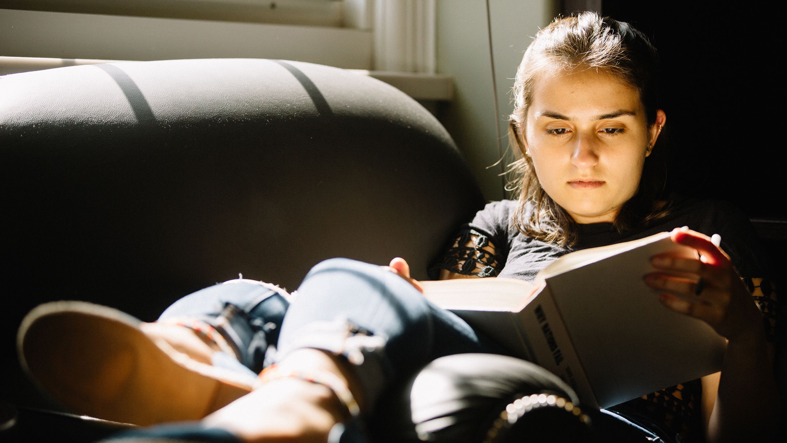 Girl sitting in chair reading book