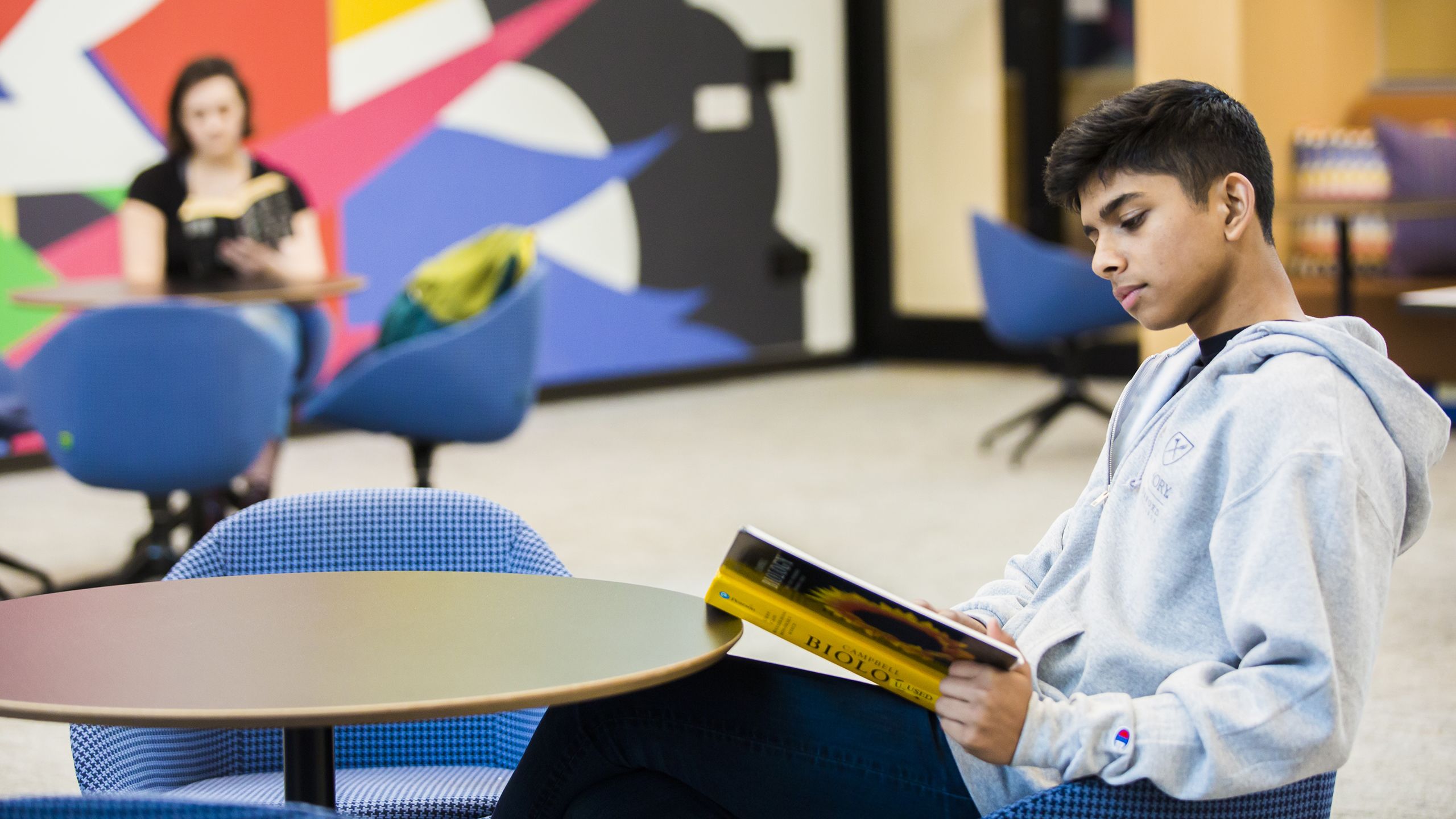 Student reading a book at a table in the Oxford Student Center