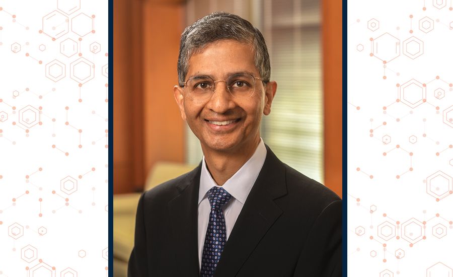 A portrait of Vikas Sukhatme smiling in a hallway in Emory's school of medicine building.