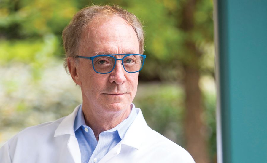 a portrait of George Painter taking outside in a white lab coat