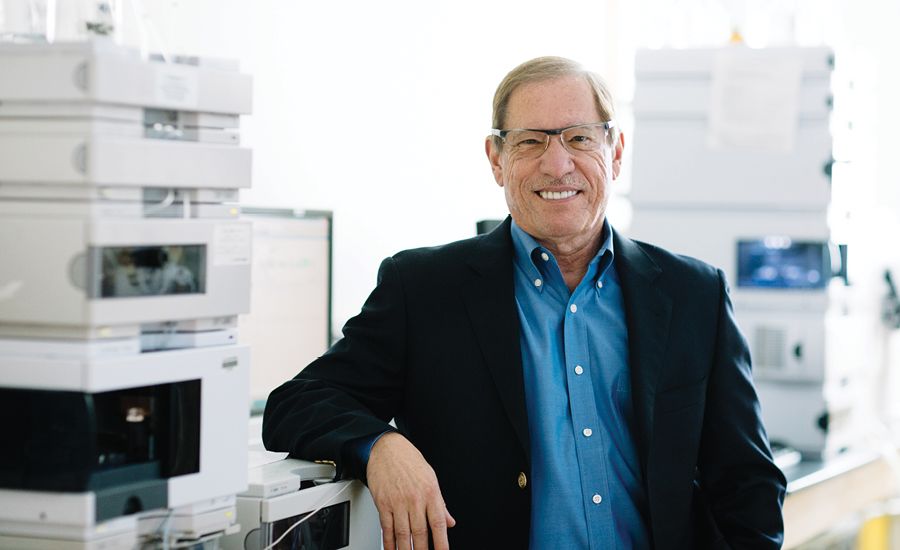 a portrait of dennis liotta standing in his research lab in front of medical equipments.