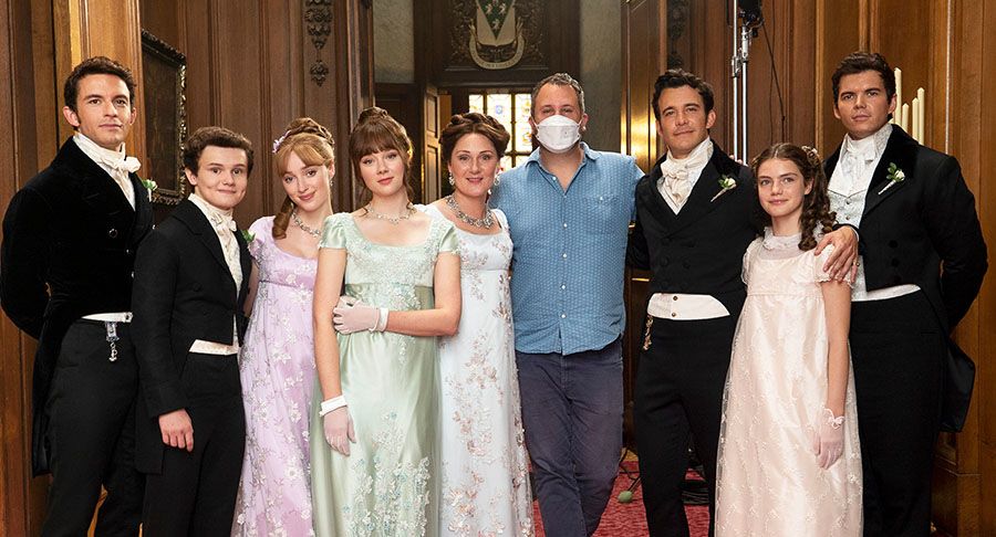 Van Dusen (blue shirt, masked) poses with the actors who portray the Bridgerton family in the series.