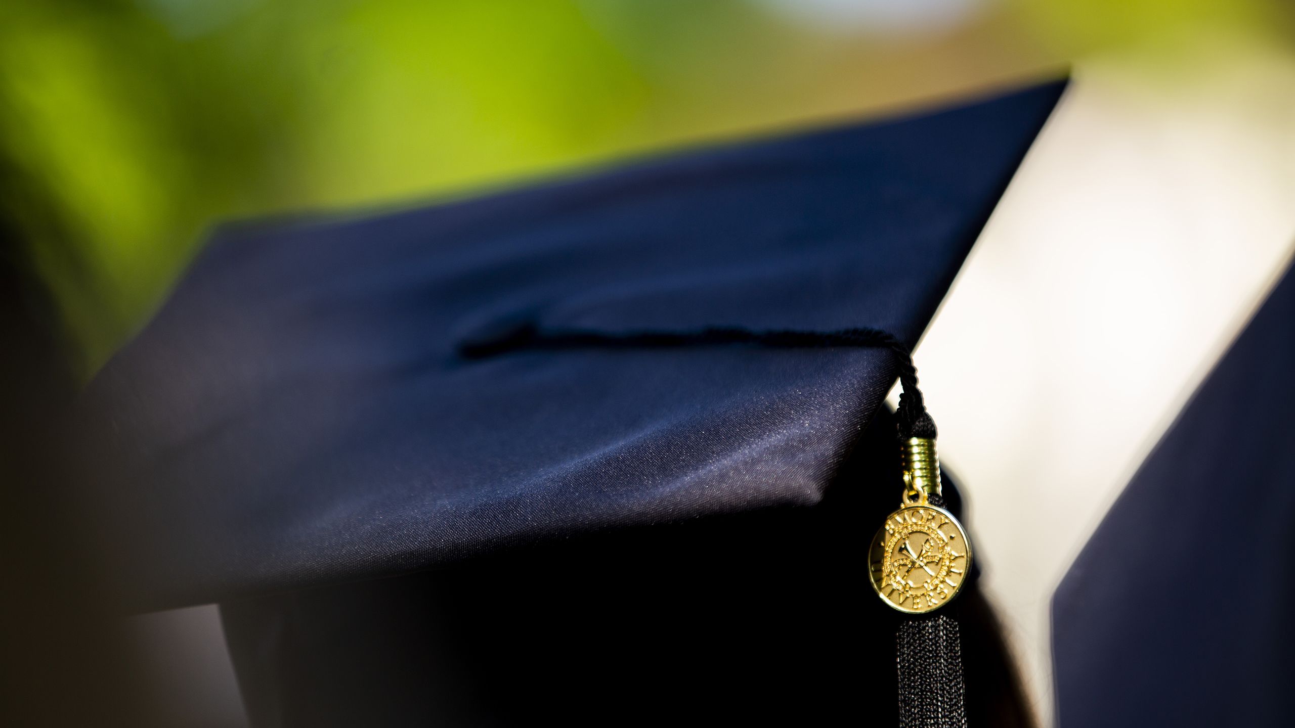 A background photo of students in caps and gowns at commencement