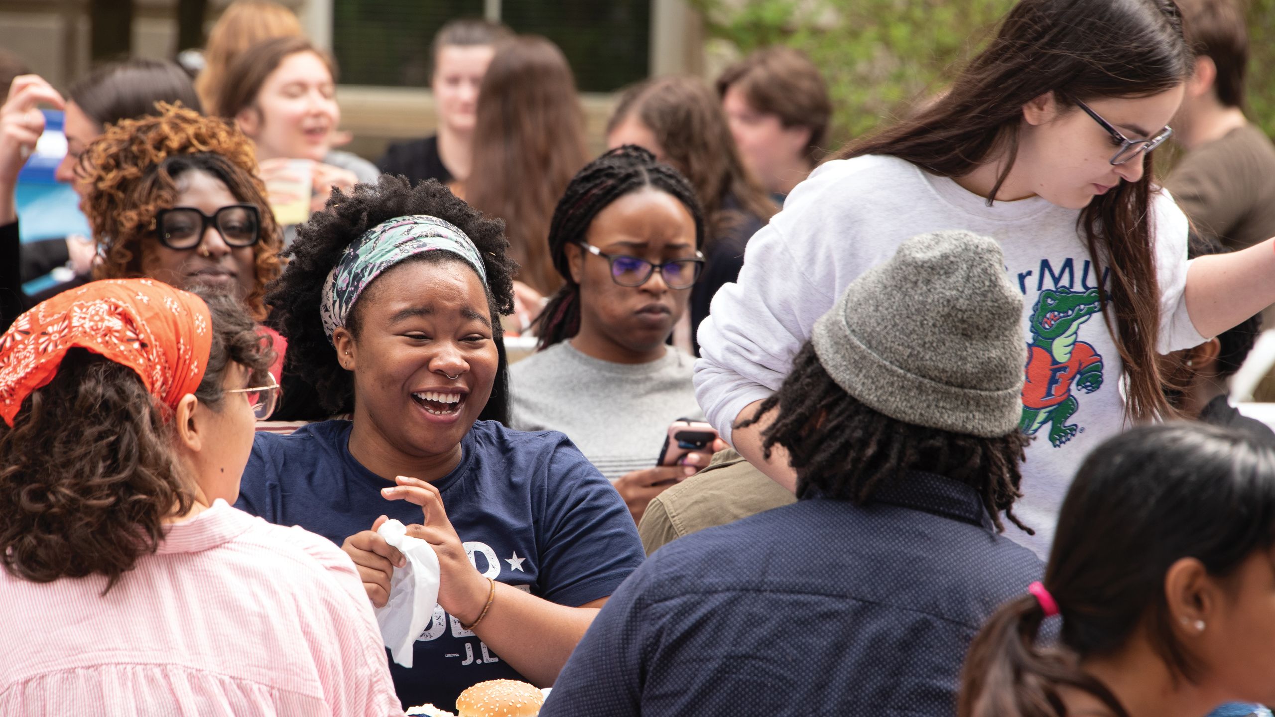 A woman laughs, surrounded by other people