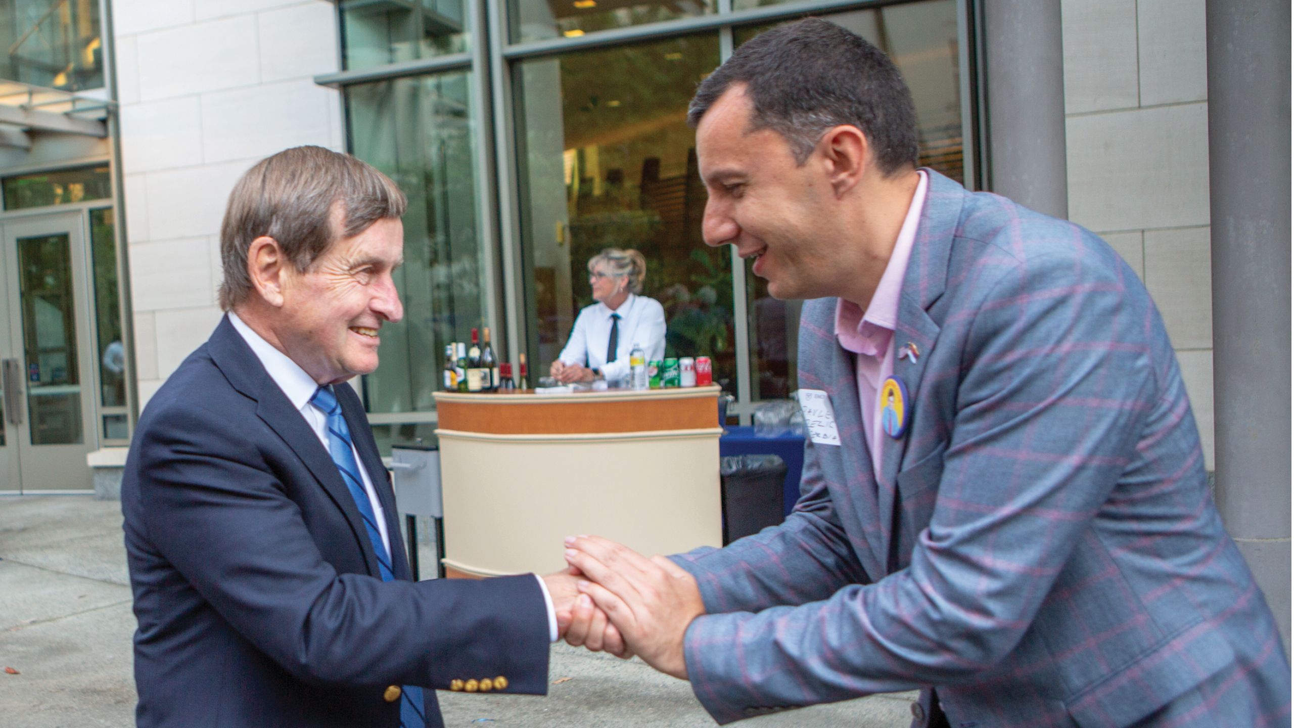 A tall man shakes hands with a shorter man.