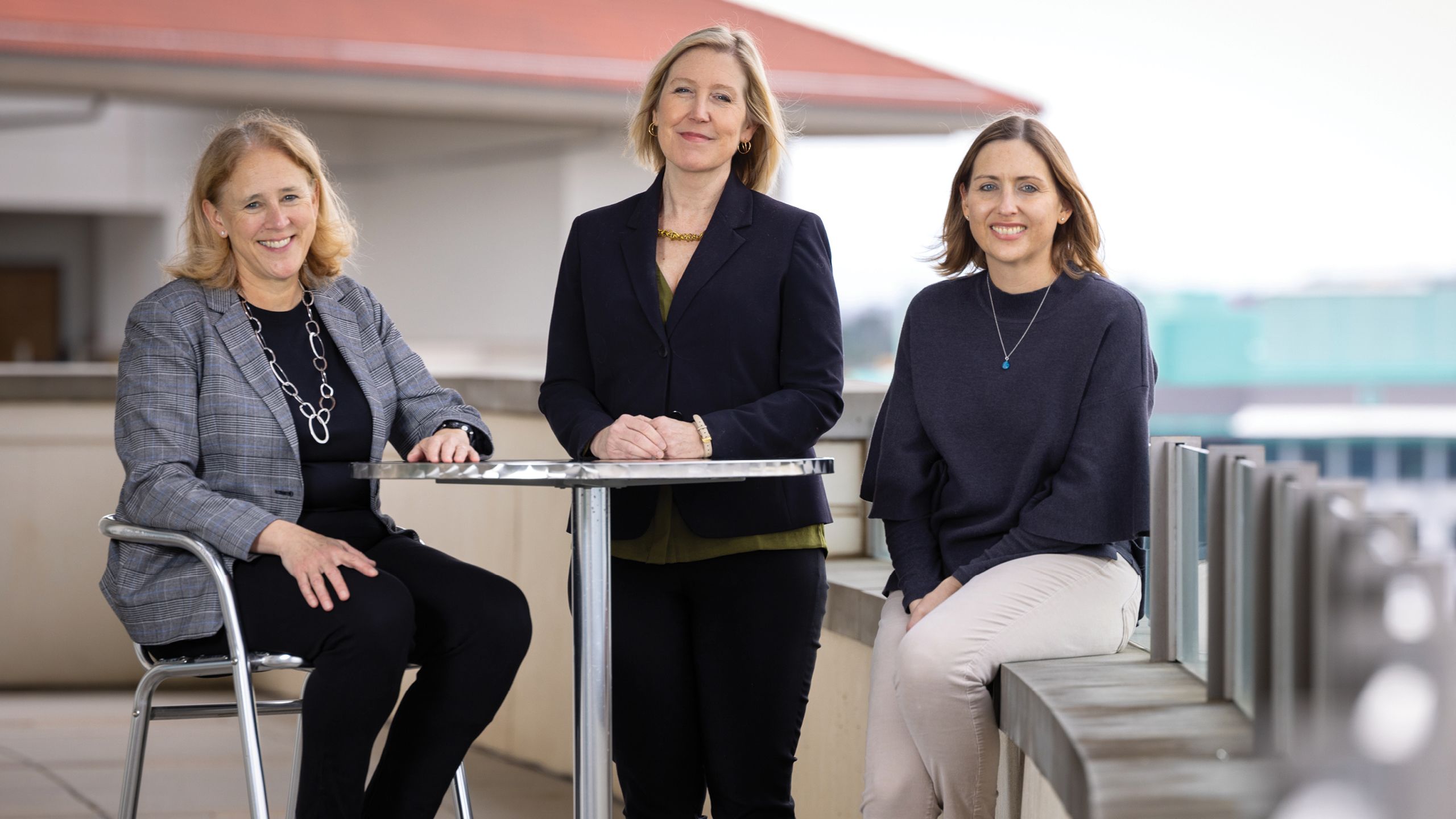 THREE WOMEN IN A GROUP SMILING FOR THE CAMERAS.