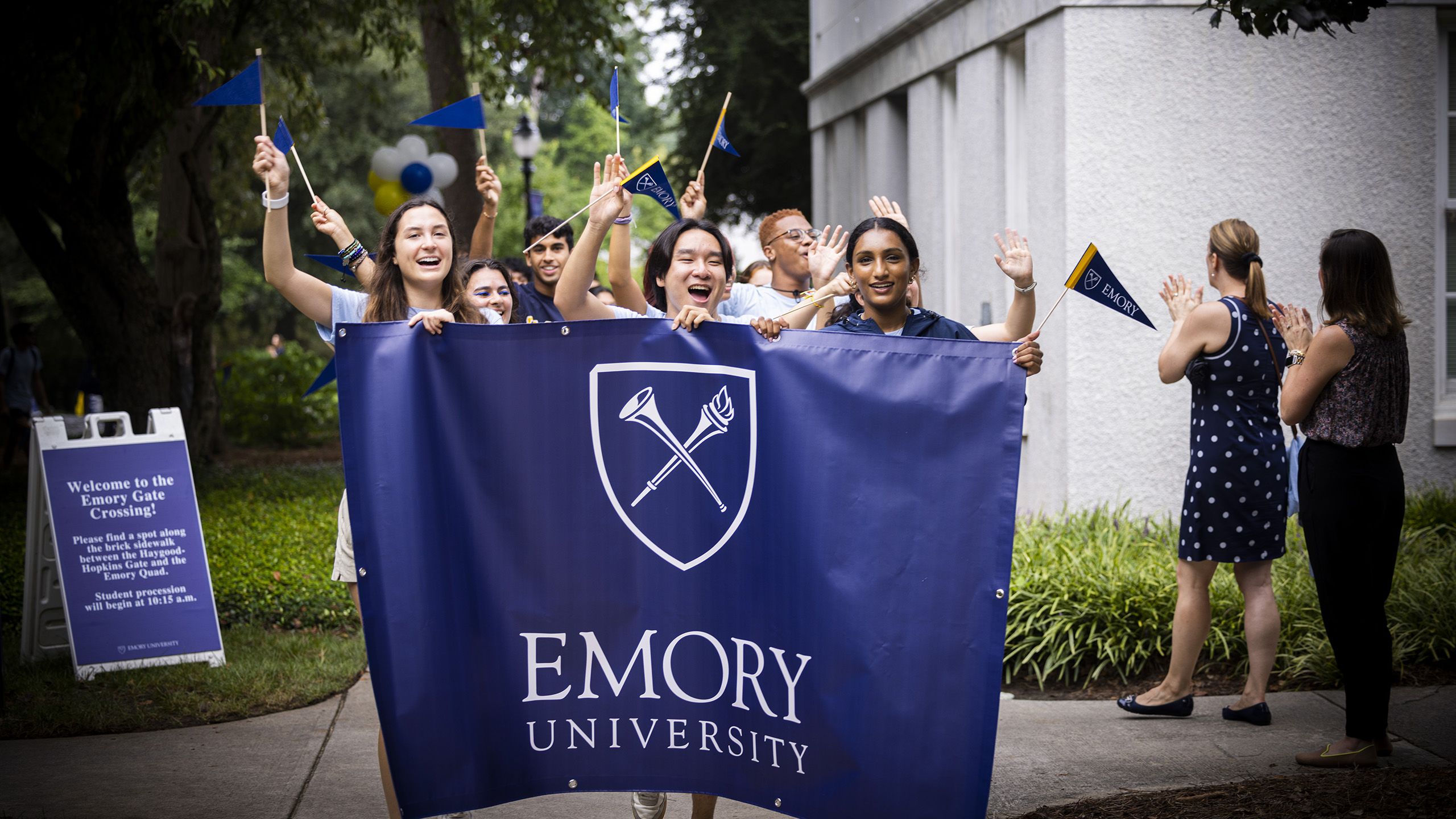 Group of students walking with Emory banner