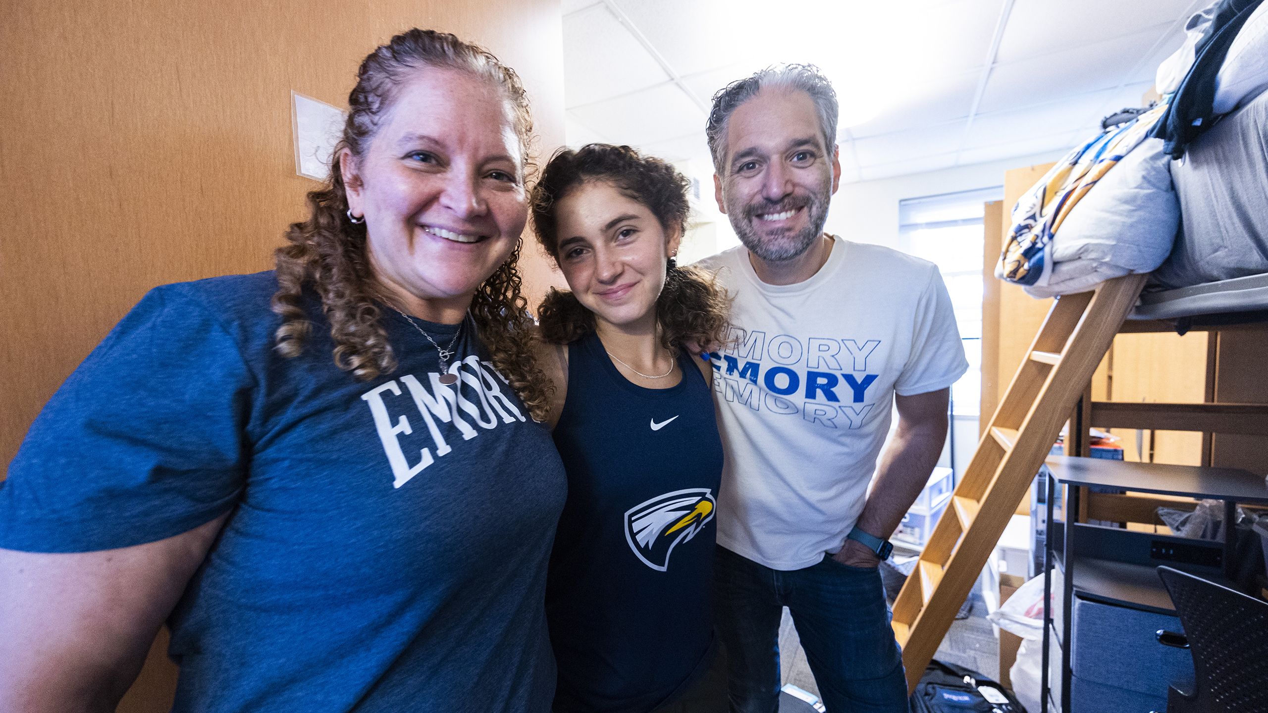 Student hugging parents in dorm room
