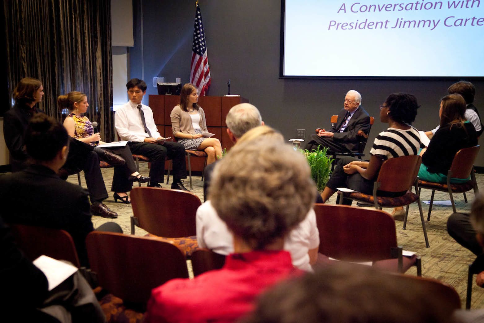 Emory students are seated in a circle around President Carter.