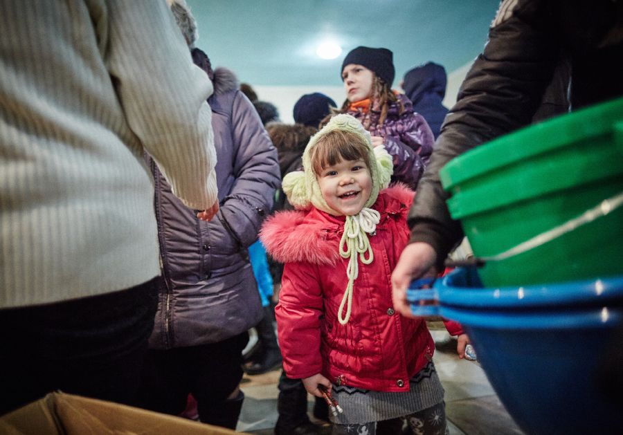 Photo of young girl in pink coat among a crowd of Ukrainian refugees.