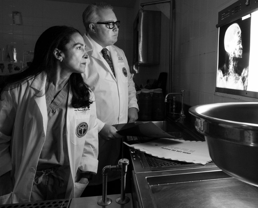 Michele Slone and Jason Graham look at an x-ray in a darkened autopsy room.