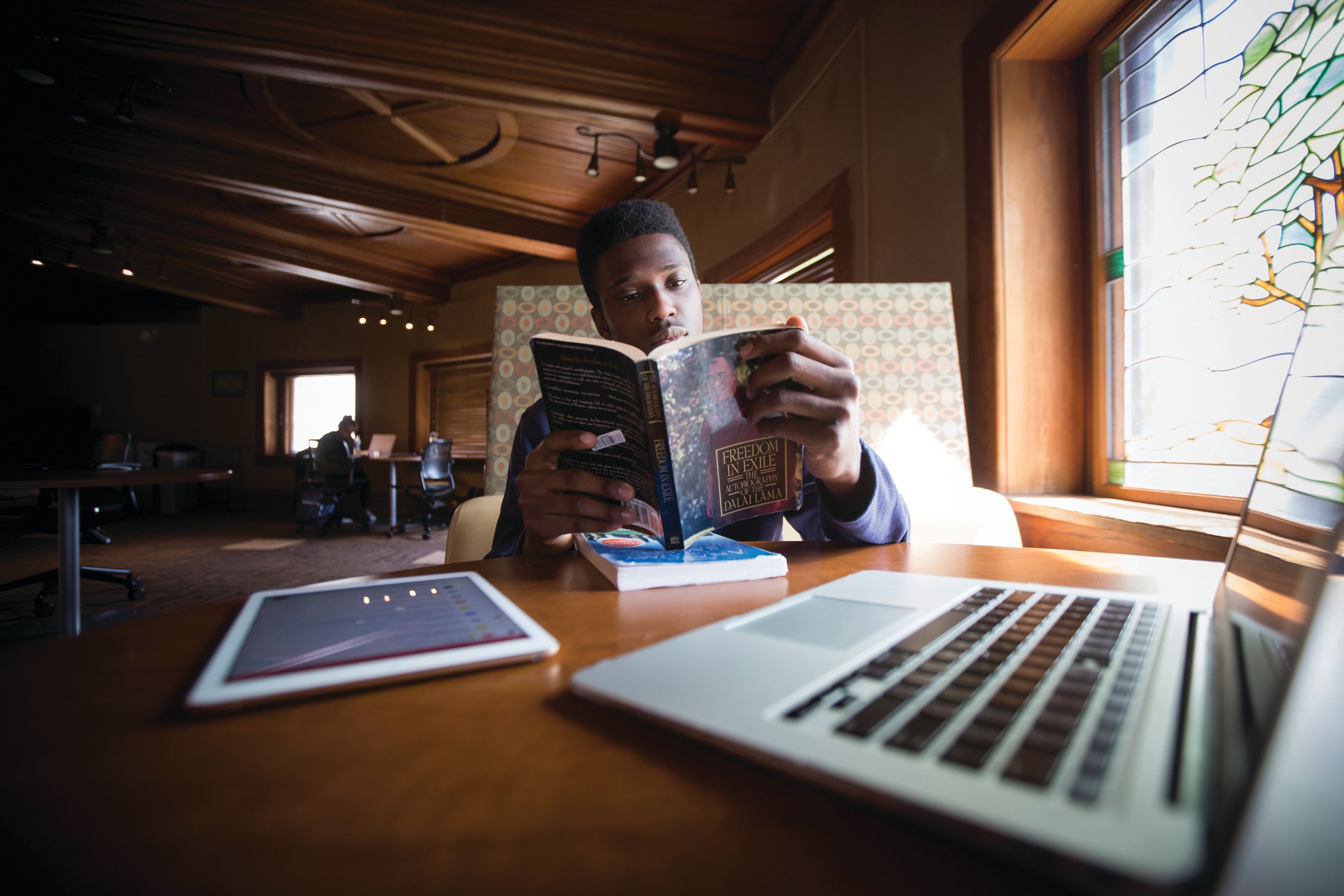 Student reading a book at a table