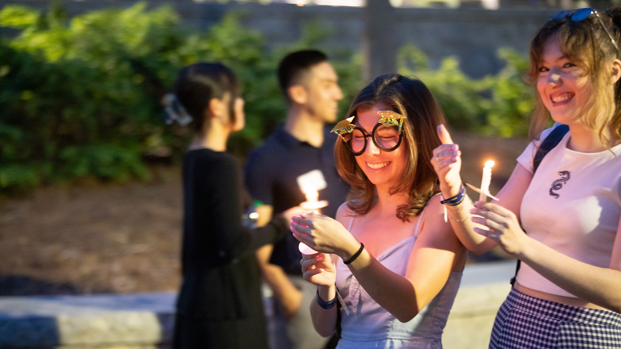 Female graduates holding candles as they cross over.