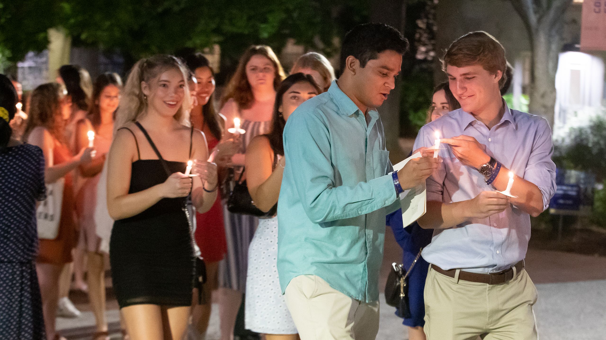 Larger crowd scene with students holding candles.