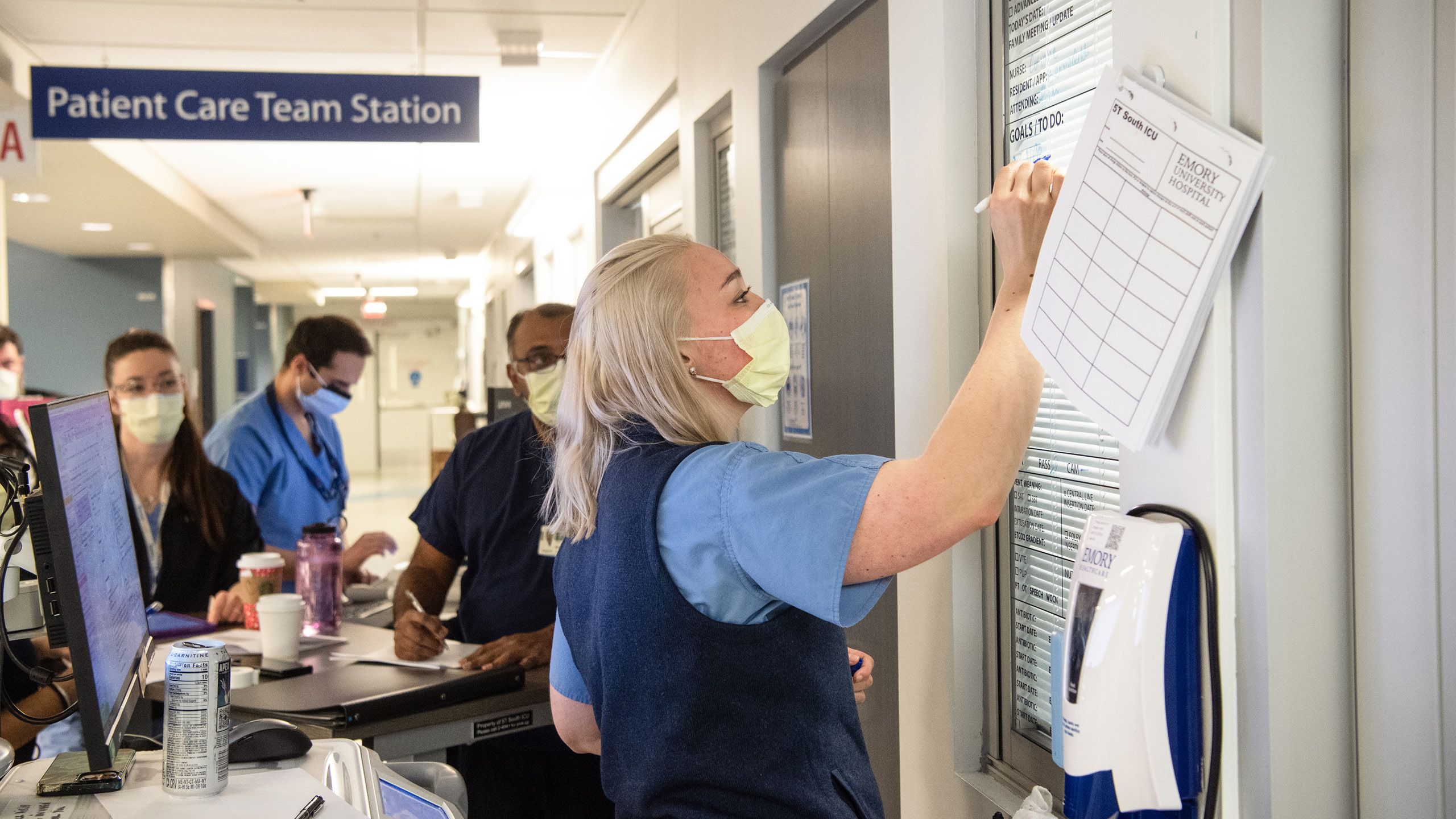 A healthcare worker updates a whiteboard in the critical care unit.