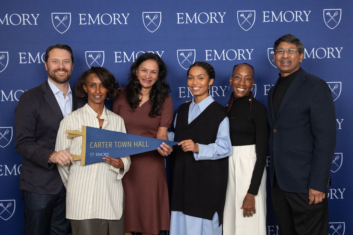 Yara Shahidi stands with members of Emory's campus leadership and a Carter Town Hall pennant.