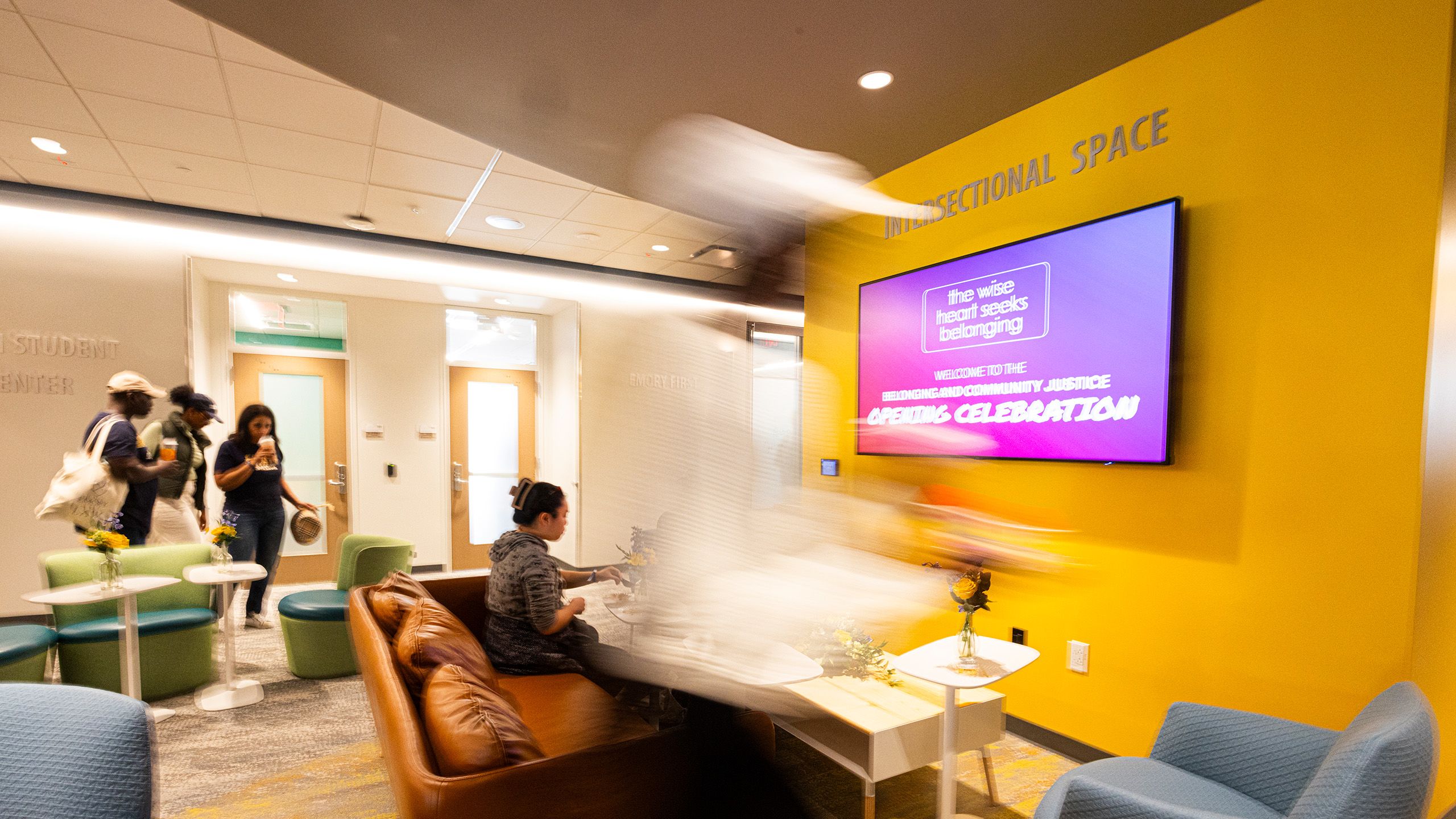 An interior photo of the Identity Spaces shows students visiting and a digital sign for the opening celebration.