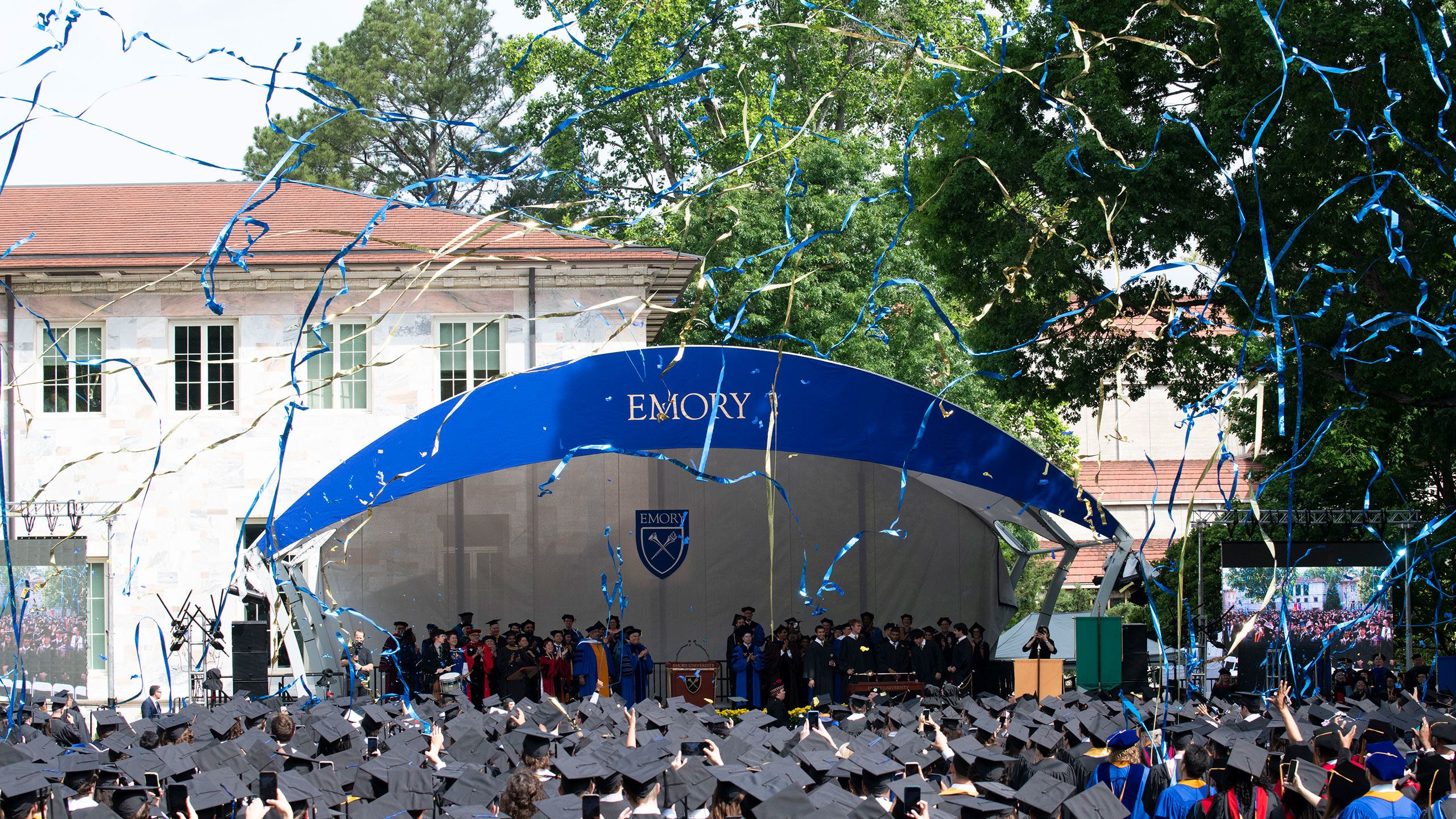 Emory Commencement concludes with blue and gold streamers flying through the air as graduates in caps and gowns watch