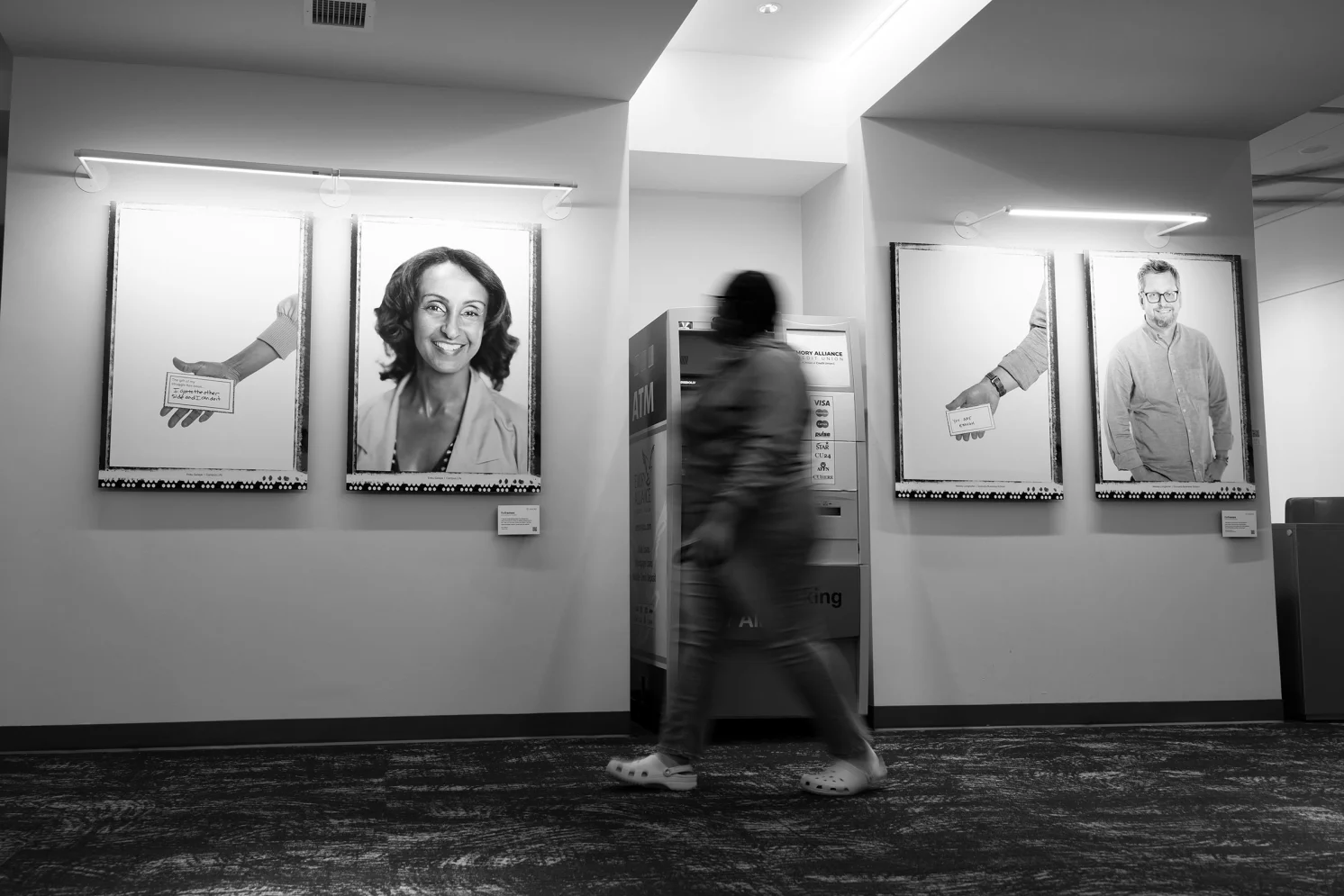 Photo of person walking past Reframe images on a wall.