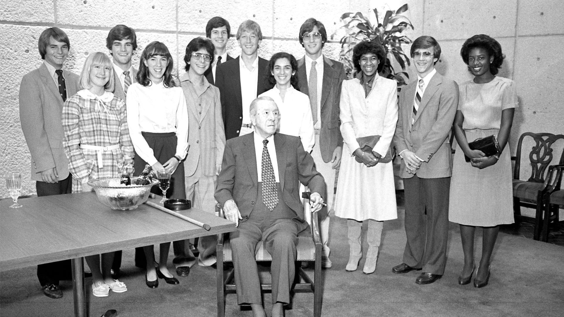 Woodruff, seated, is surrounded by a group of students.