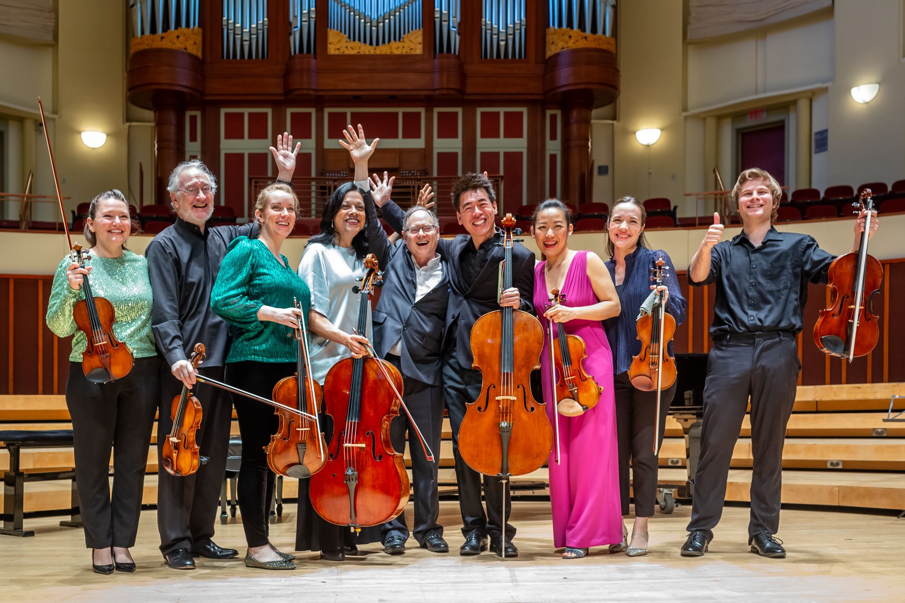 A group of musicians hold instruments and wave