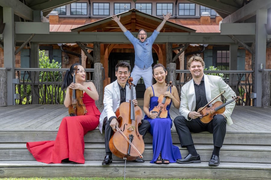 Members of the Vega Quartet sit in the foreground, while William Ransom jumps up in the air in the background.