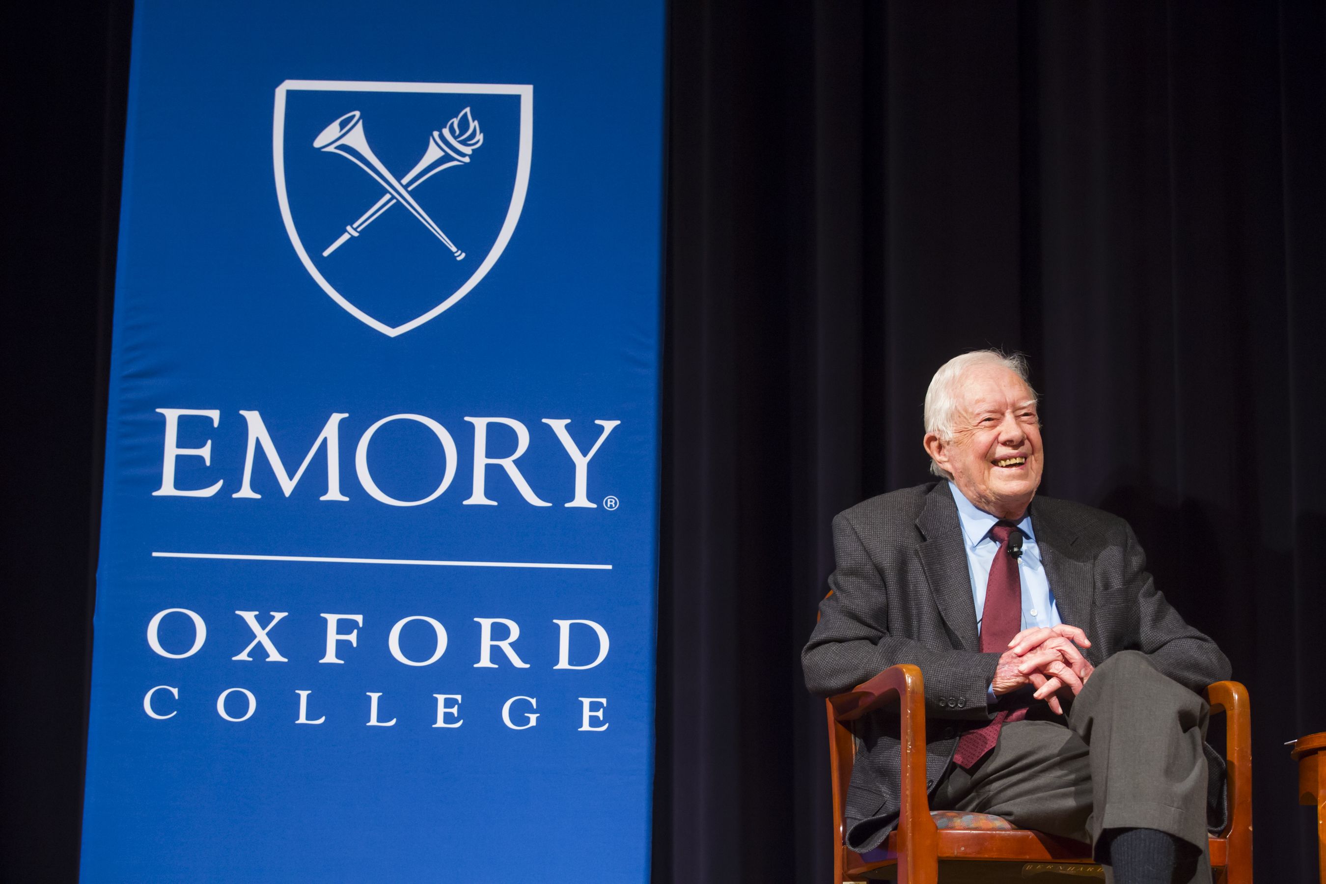 Carter, seated, next to a blue Emory Oxford College banner.