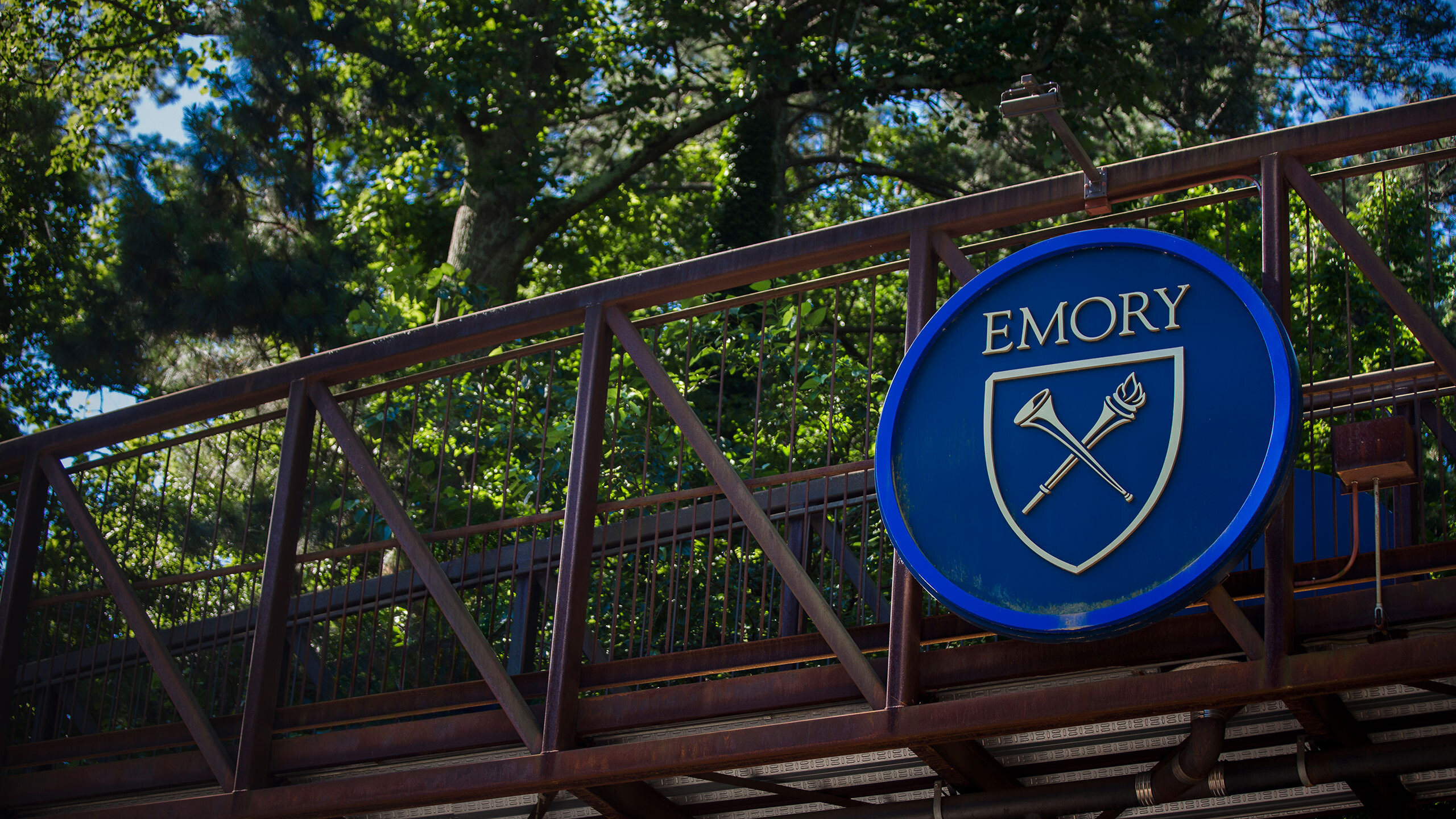 A photo of the Emory emblem on the pedestrian bridge across Houston Mill Road