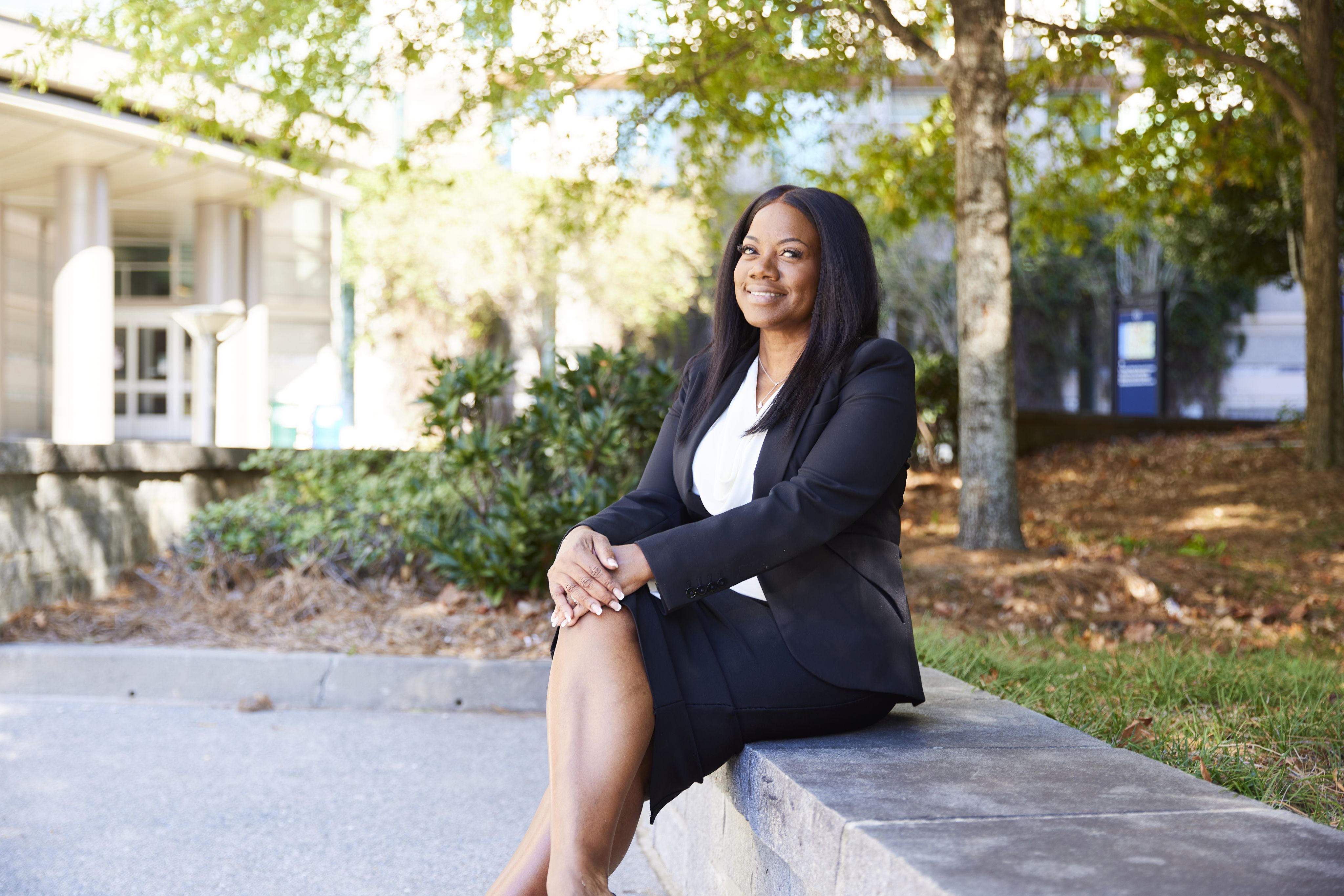 Black woman in a suit sitting outdoors