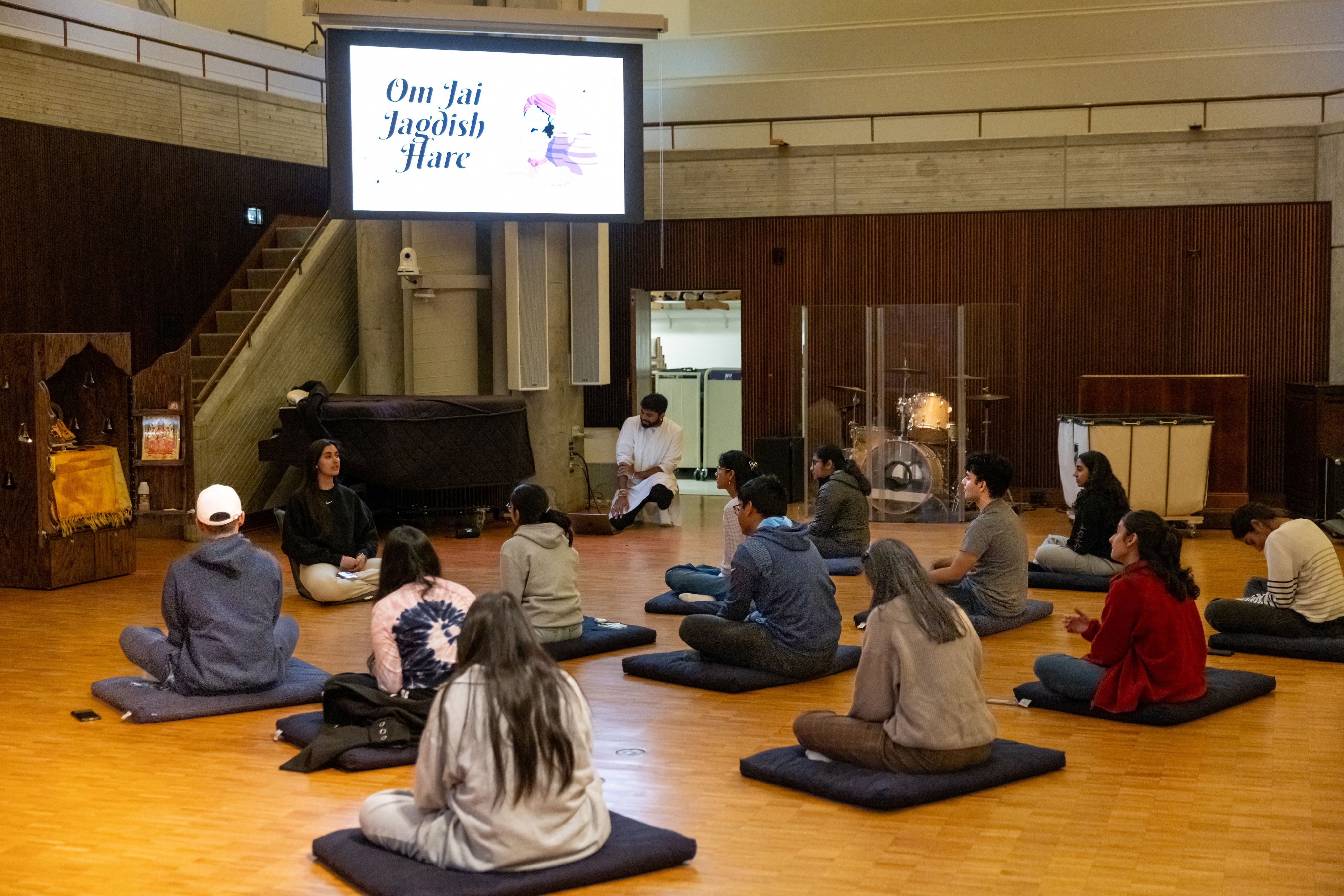 Persaud leading a group in prayer, all seated on mats